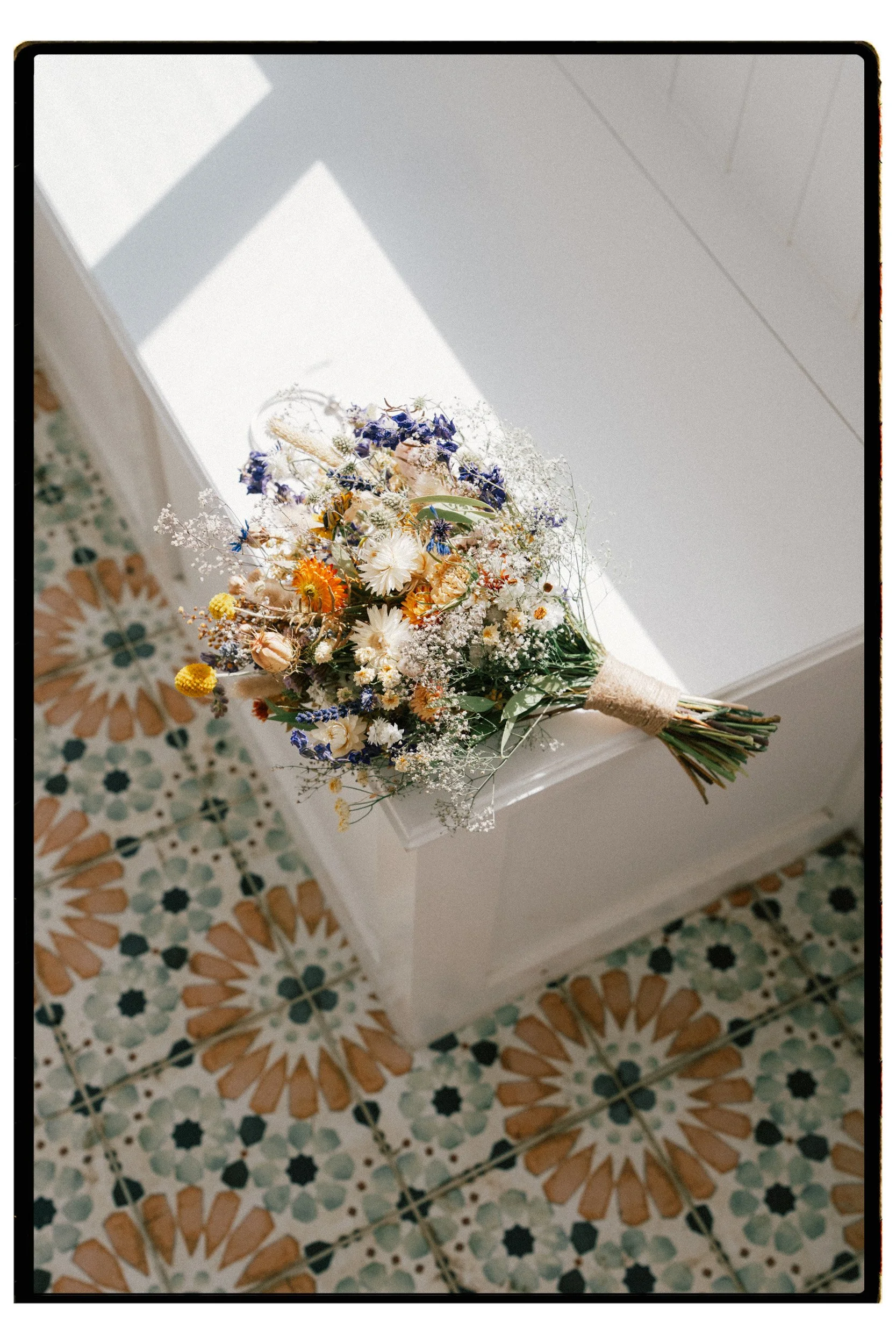 Christchurch, Queenstown, Dunedin Film & Digital Wedding Photography.  A coluorful bouquet of mixed flowers resting on a white surface, with patterned tile flooring beneath.