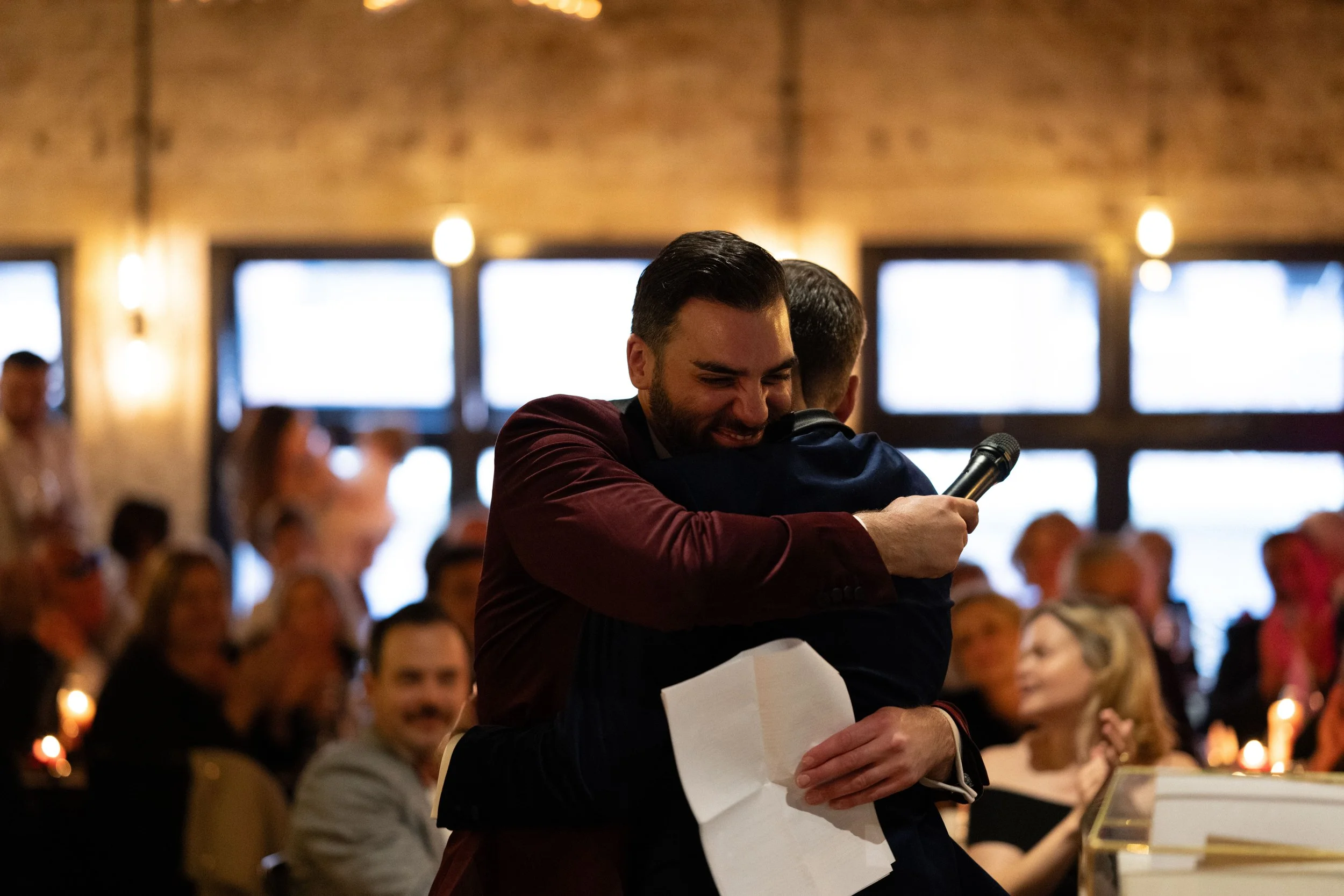 Grooms hug each other after wedding speech.