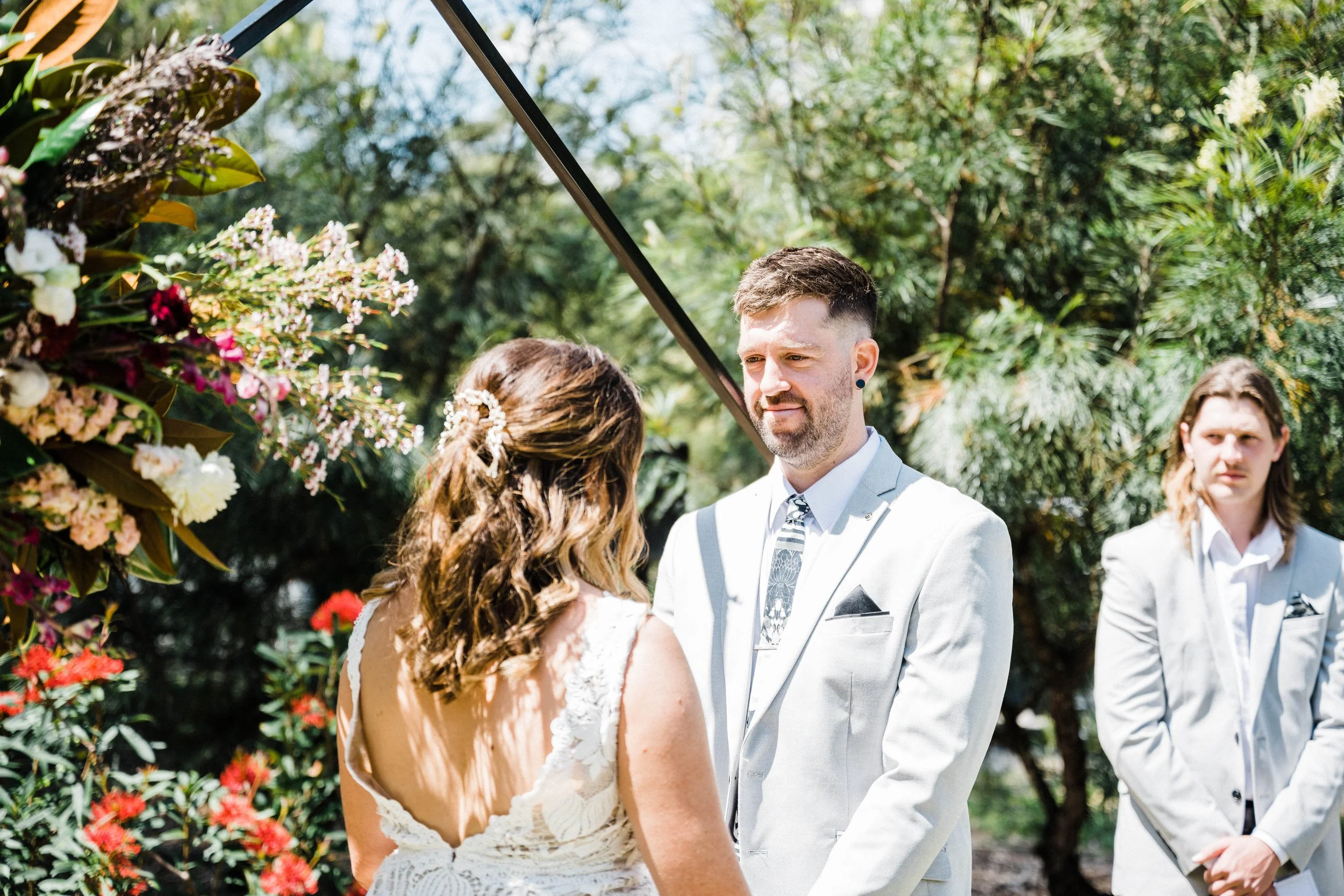 Bride and groom looking at each other in front of flower wedding altar.