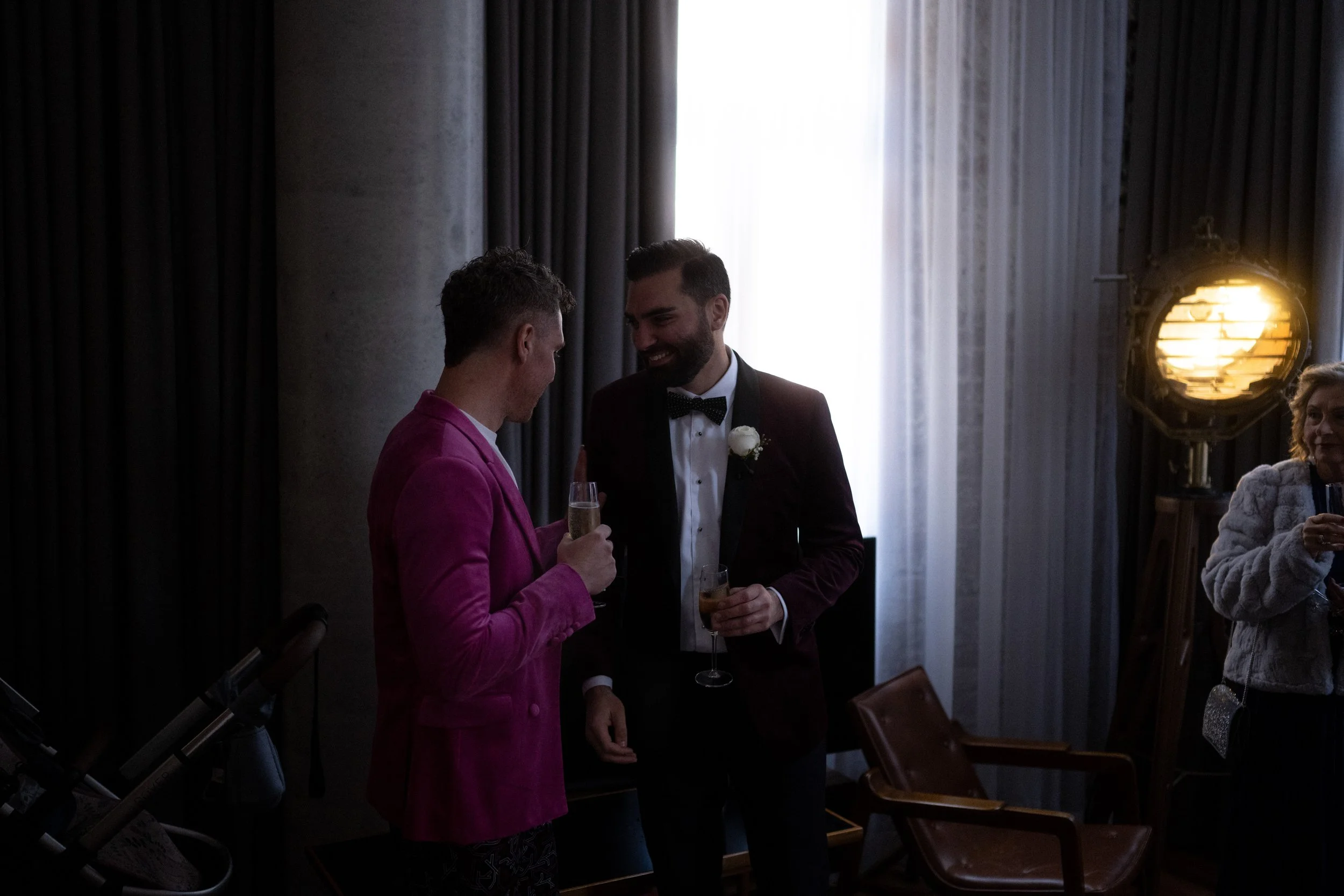 Cinematic and moody photo of groom talking to guests in hotel room.