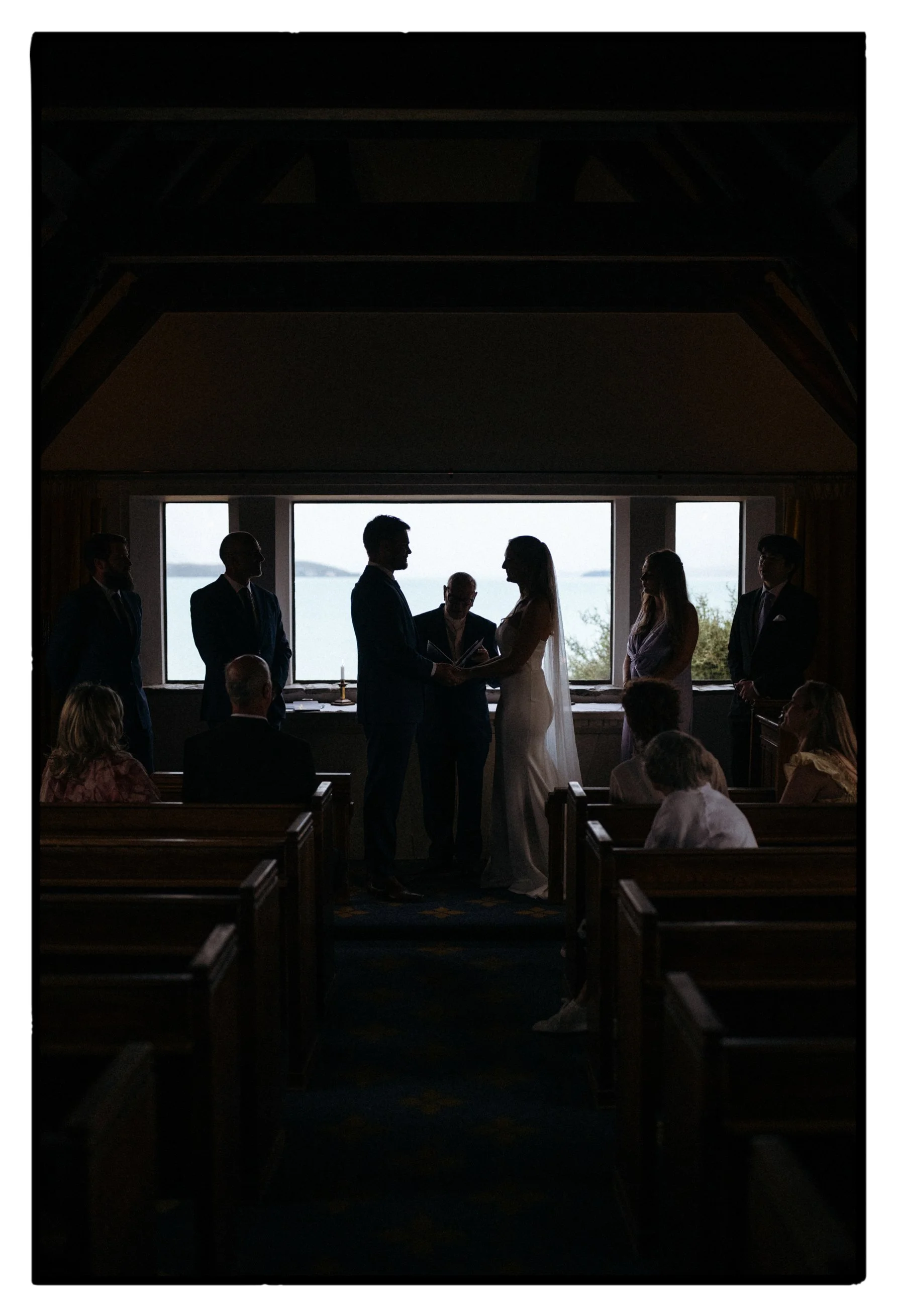 Film + Digital Wedding Photographer Christchurch - Lake Tekapo Wedding, Canterbury, New Zealand. Wedding ceremony inside Church of the Good Shepherd on a rainy day. You can see the mountains and lake in the background through the window.