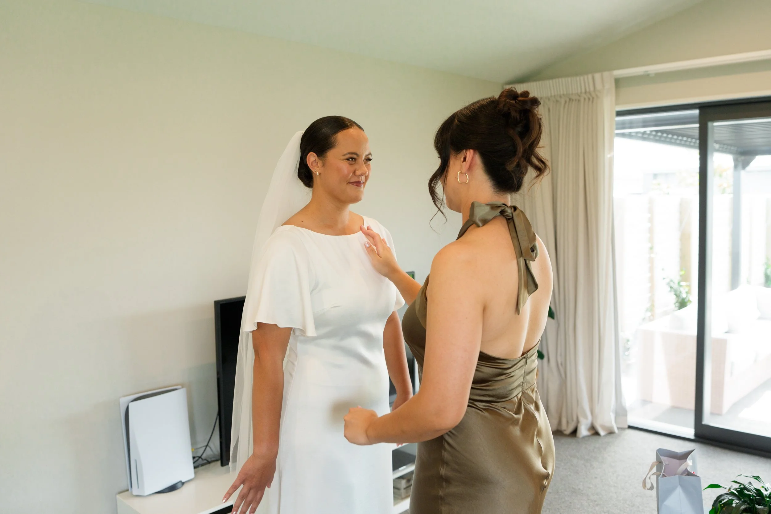 Film + Digital Wedding Photographer Christchurch - Backyard Wedding, Christchurch, Canterbury, New Zealand. Bride in white dress and veil standing face-to-face with bridesmaid in satin champagne-colored dress.