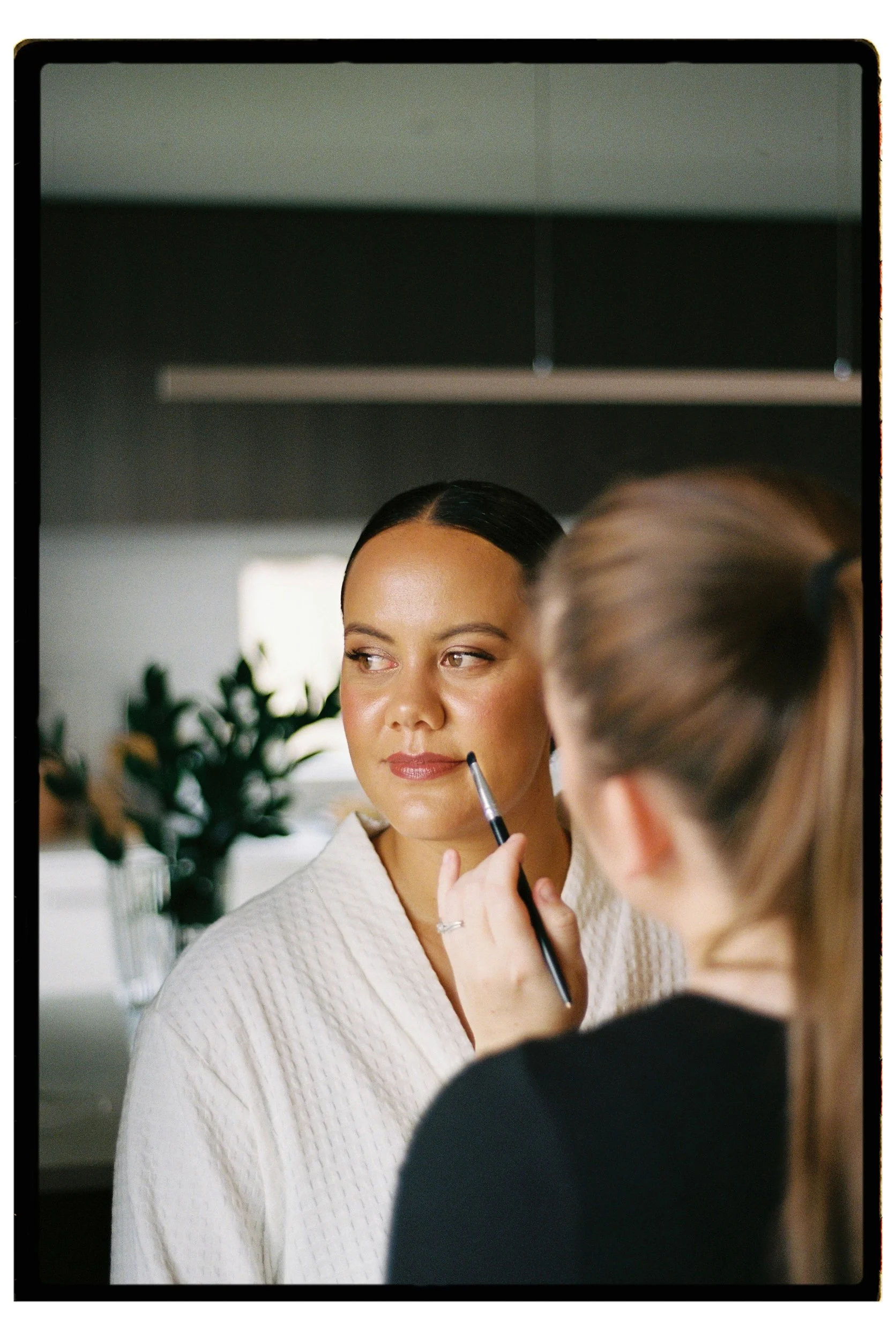 Film + Digital Wedding Photographer Christchurch - Backyard Wedding, Christchurch, Canterbury, New Zealand. Film photo of bride getting ready. Her makeup is being touched up by a makeup artist.
