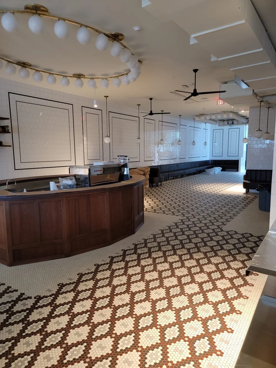 Empty cafe or restaurant interior with a curved wooden counter, patterned tile floor, white tiled walls, all tile done by MZ Flooring