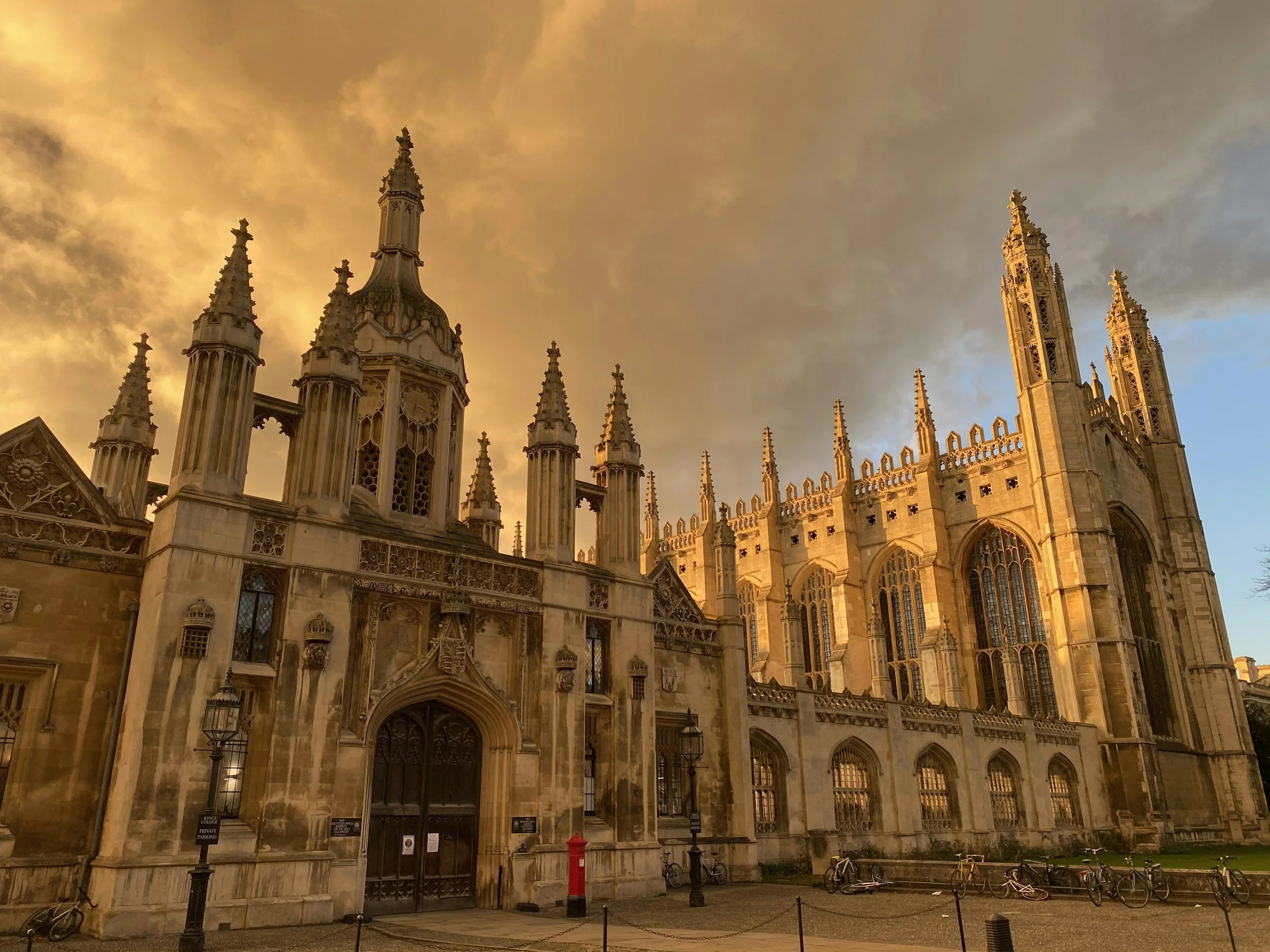 Gothic cathedral during sunset with golden skies, featuring tall spires, ornate windows, and a large main door.