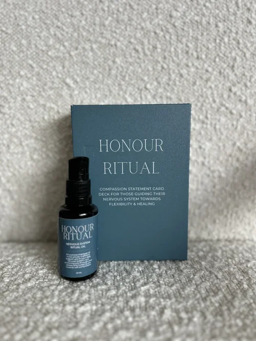 A small bottle and a blue card with the label "Honour Ritual" on a textured surface.