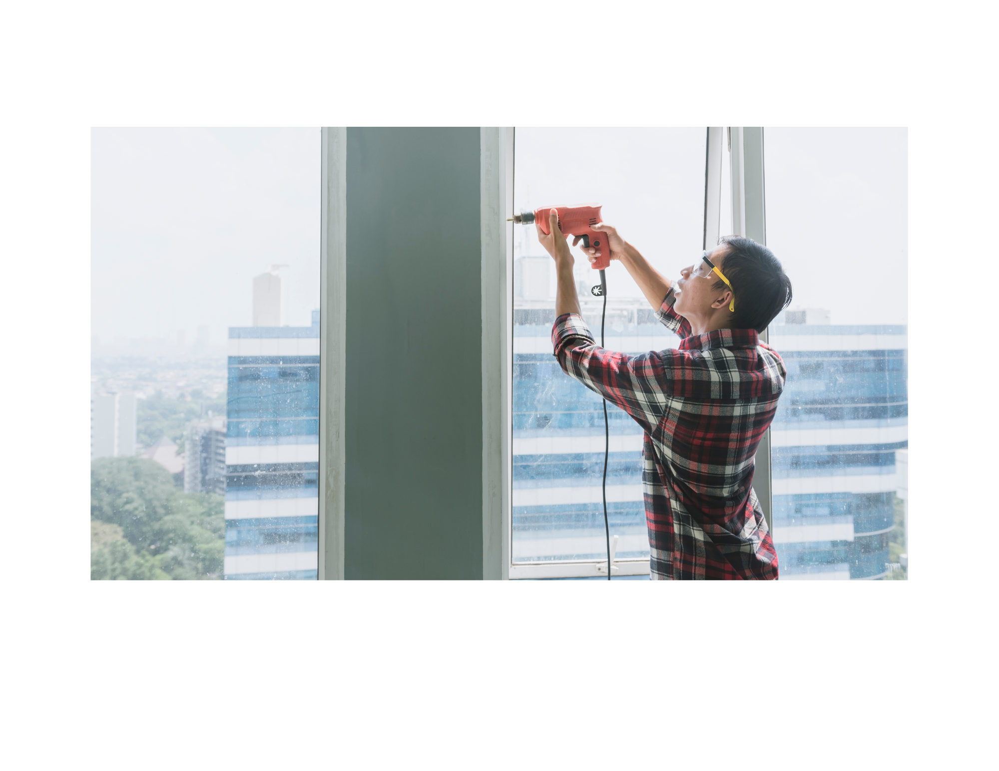 Persona instalando un protector de ventanas con una pistola de silicona en un edificio alto, con vista de la ciudad al fondo.