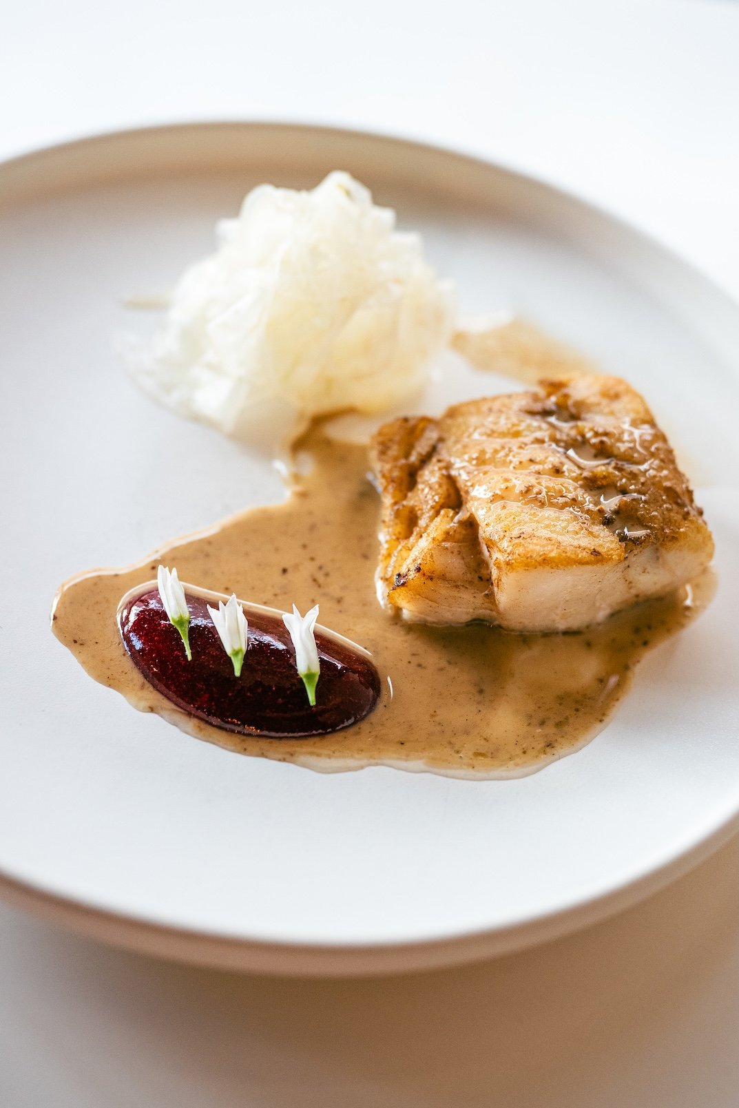 Dessert plate with sponge cake, meringue, a dollop of cream with a cherry topping, and a scoop of vanilla ice cream