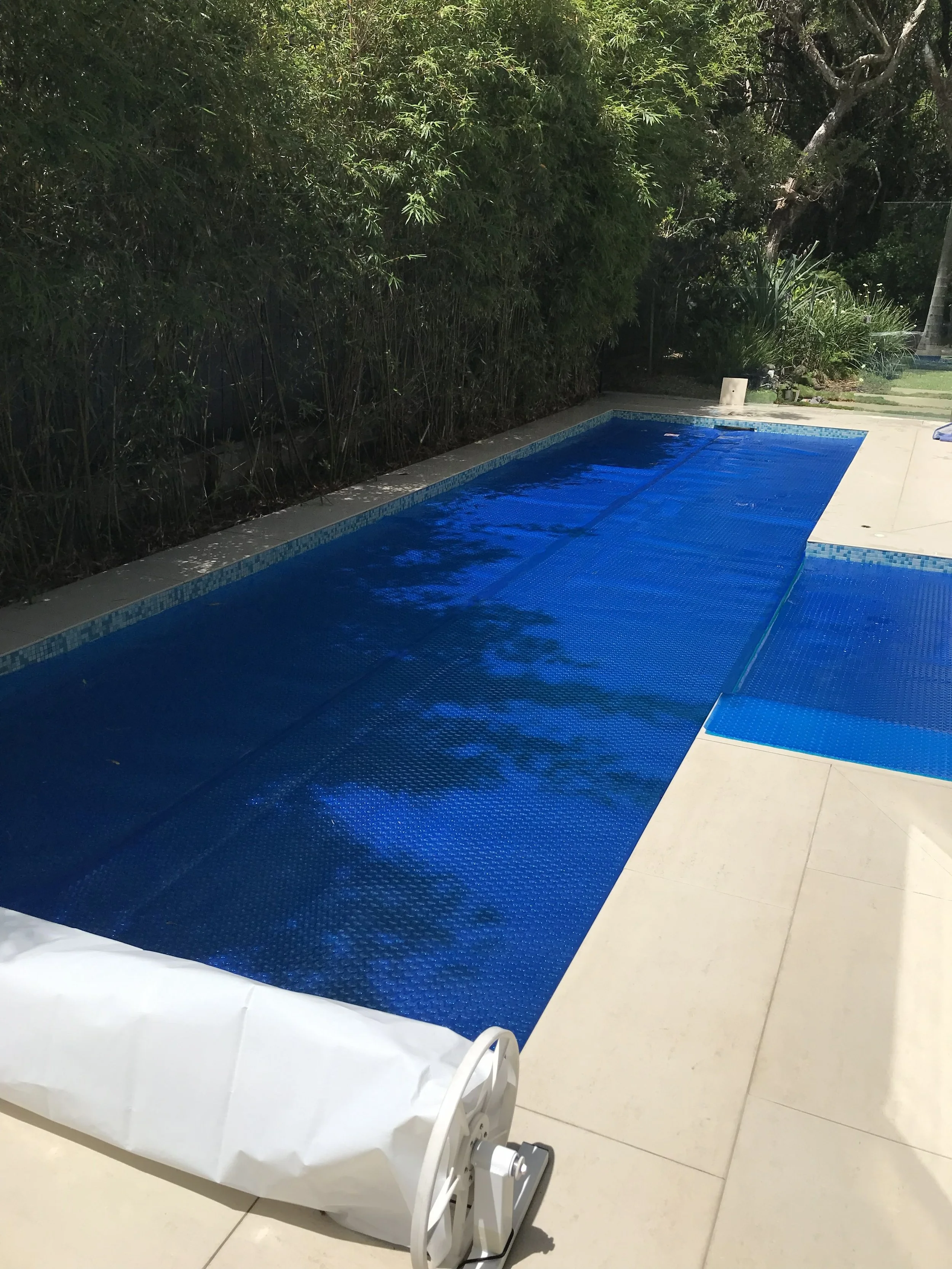 Blue bubble pool cover fitted across a backyard pool in Wurtulla