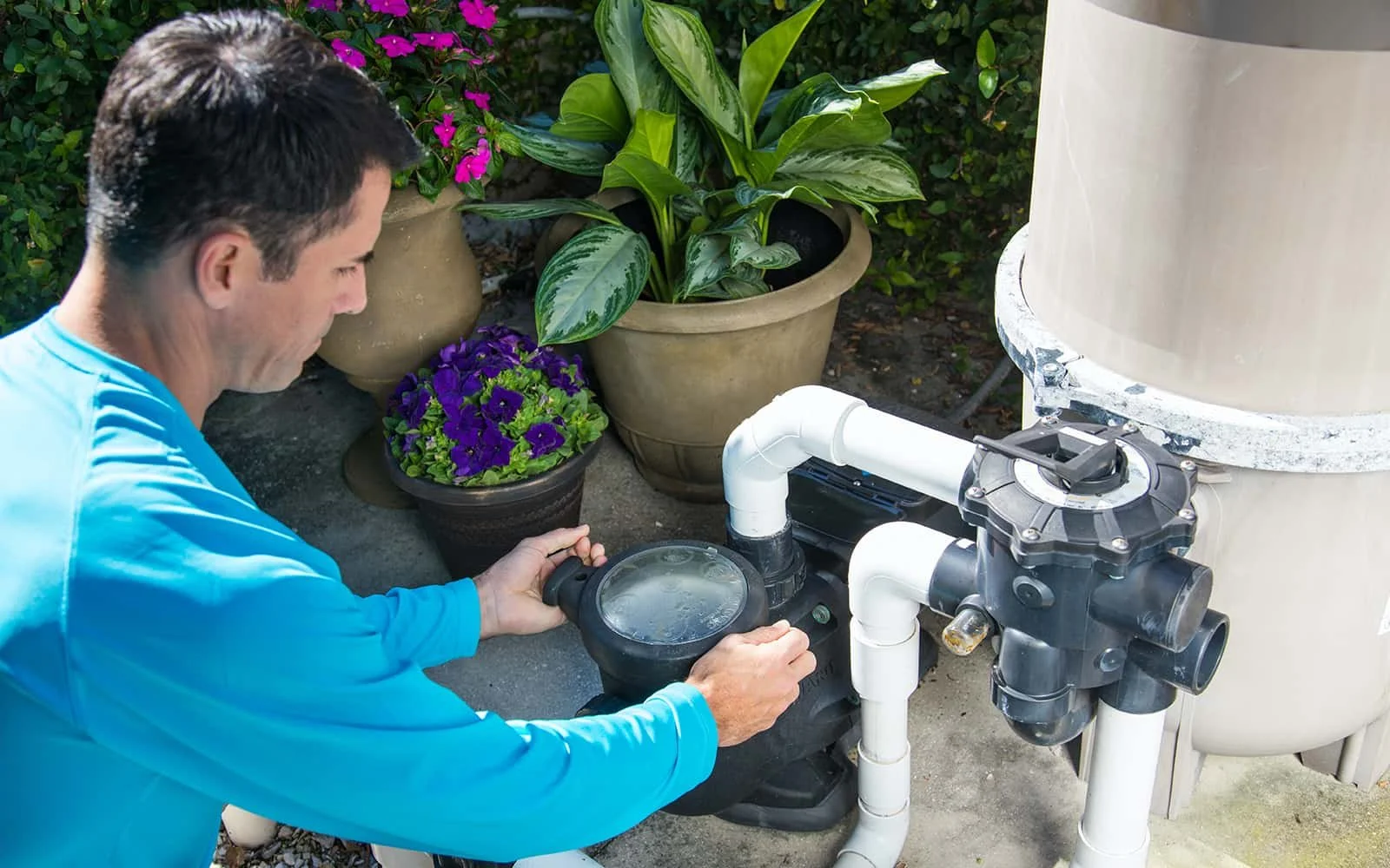 Pool technician inspecting and repairing residential pool equipment