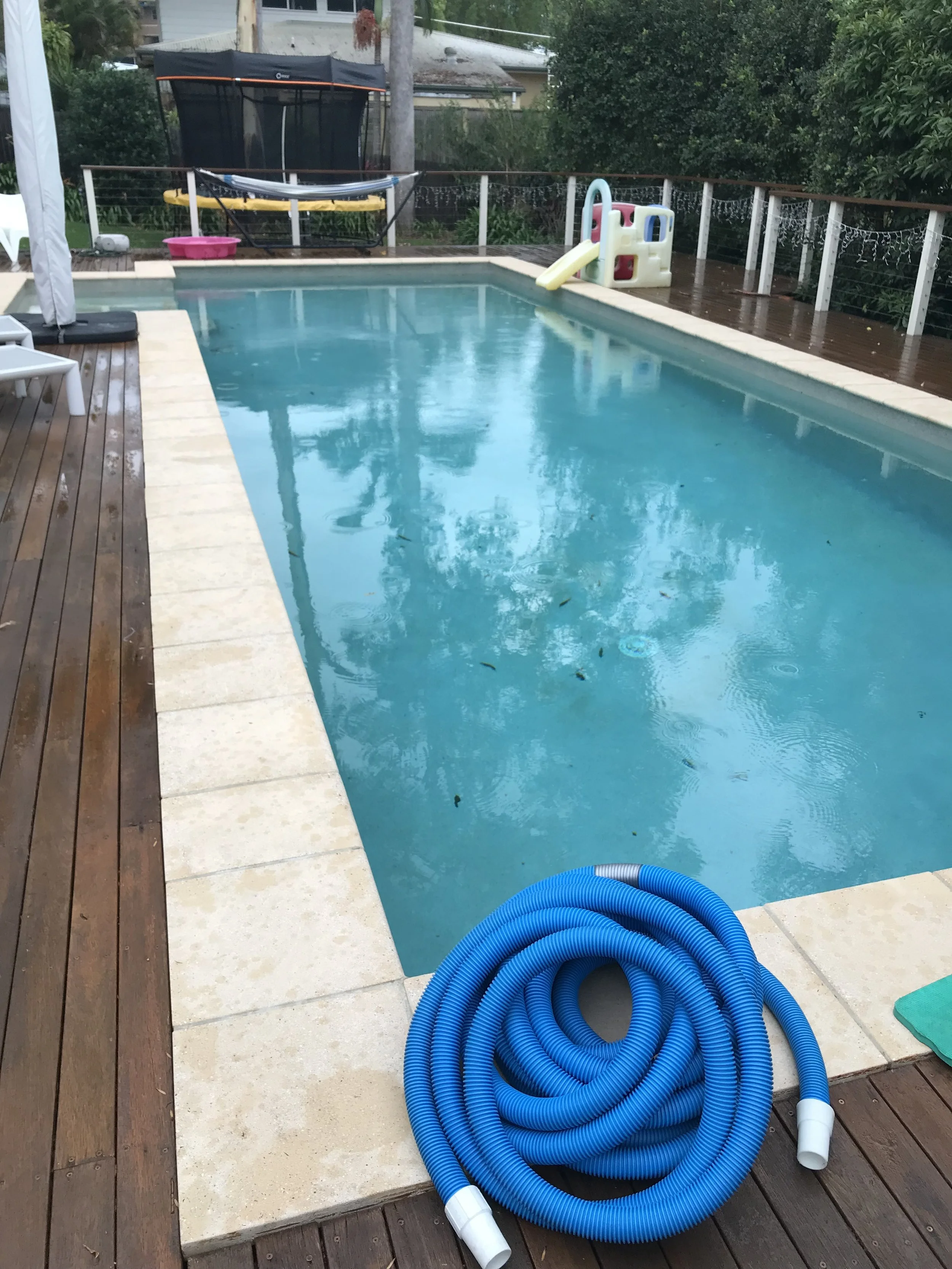 Swimming pool with cleaning hose beside a timber deck at a Buderim property.