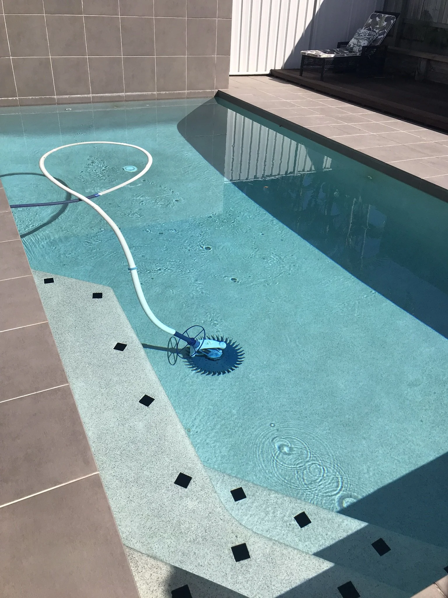 Swimming pool in Kuluin with clear blue water, submerged steps and a suction cleaner on the pool floor