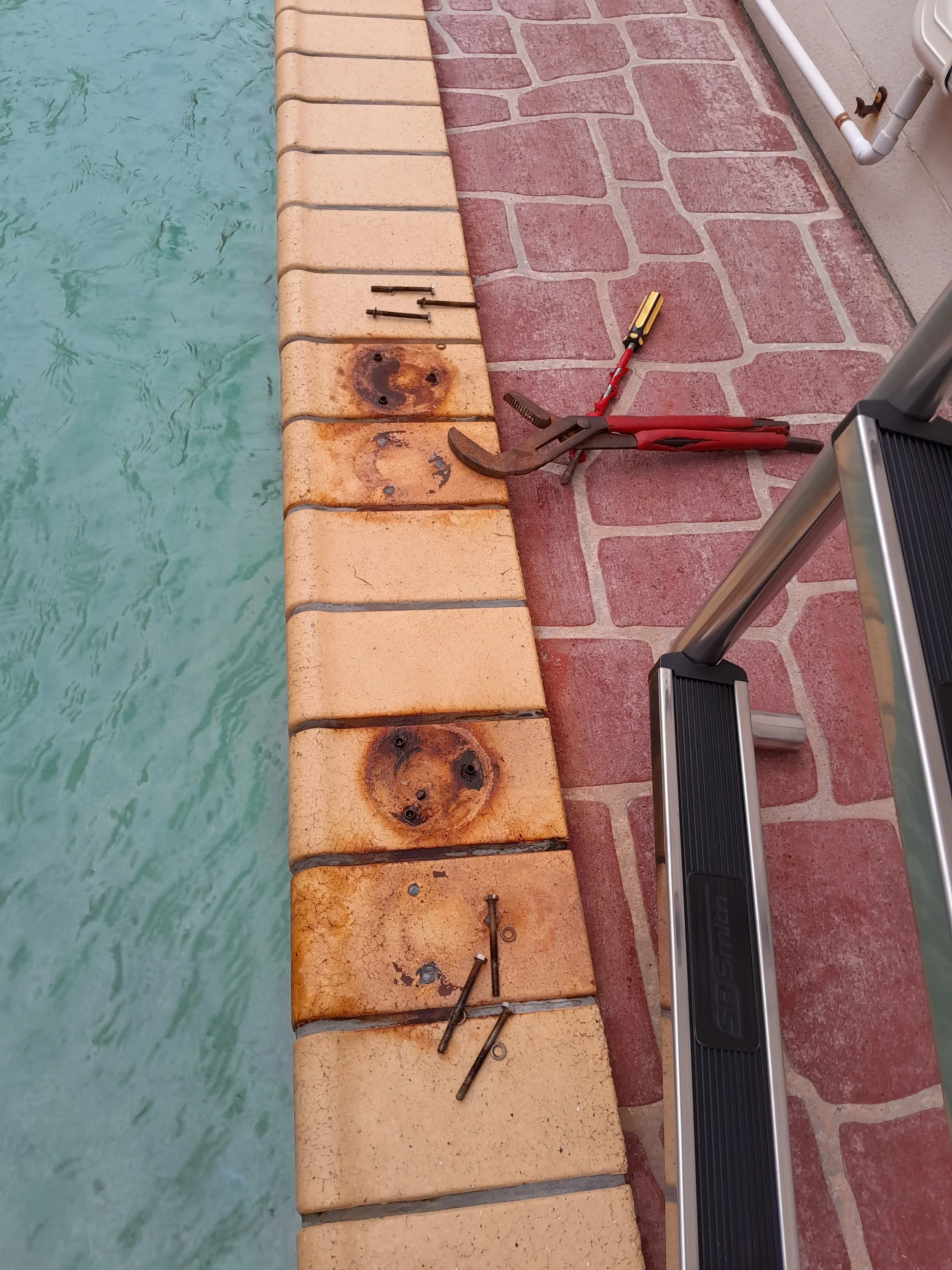 Old pool ladder removed showing previous mounting points in the pool surround