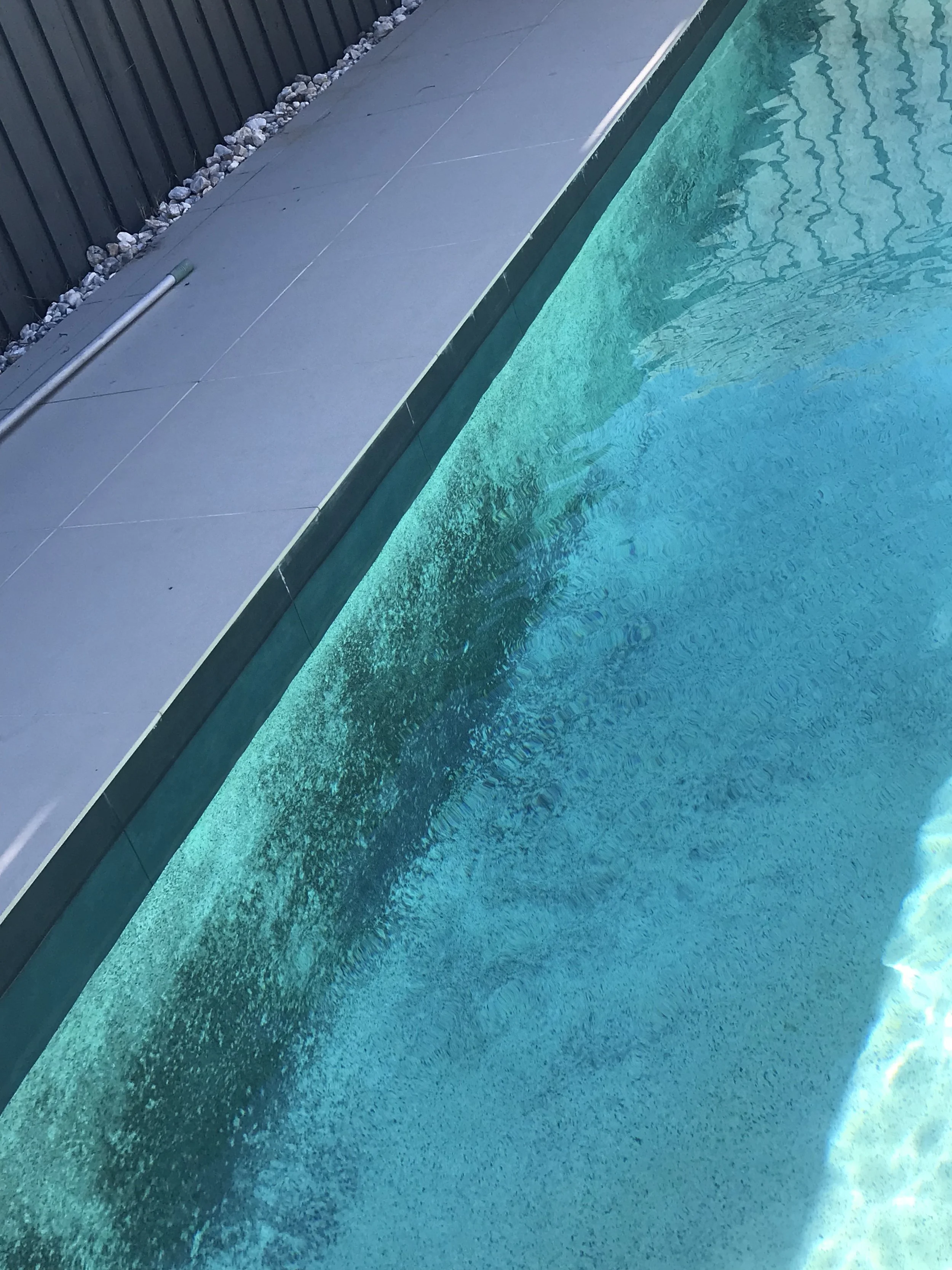 Black copper staining on the wall of a Birtinya pool before treatment