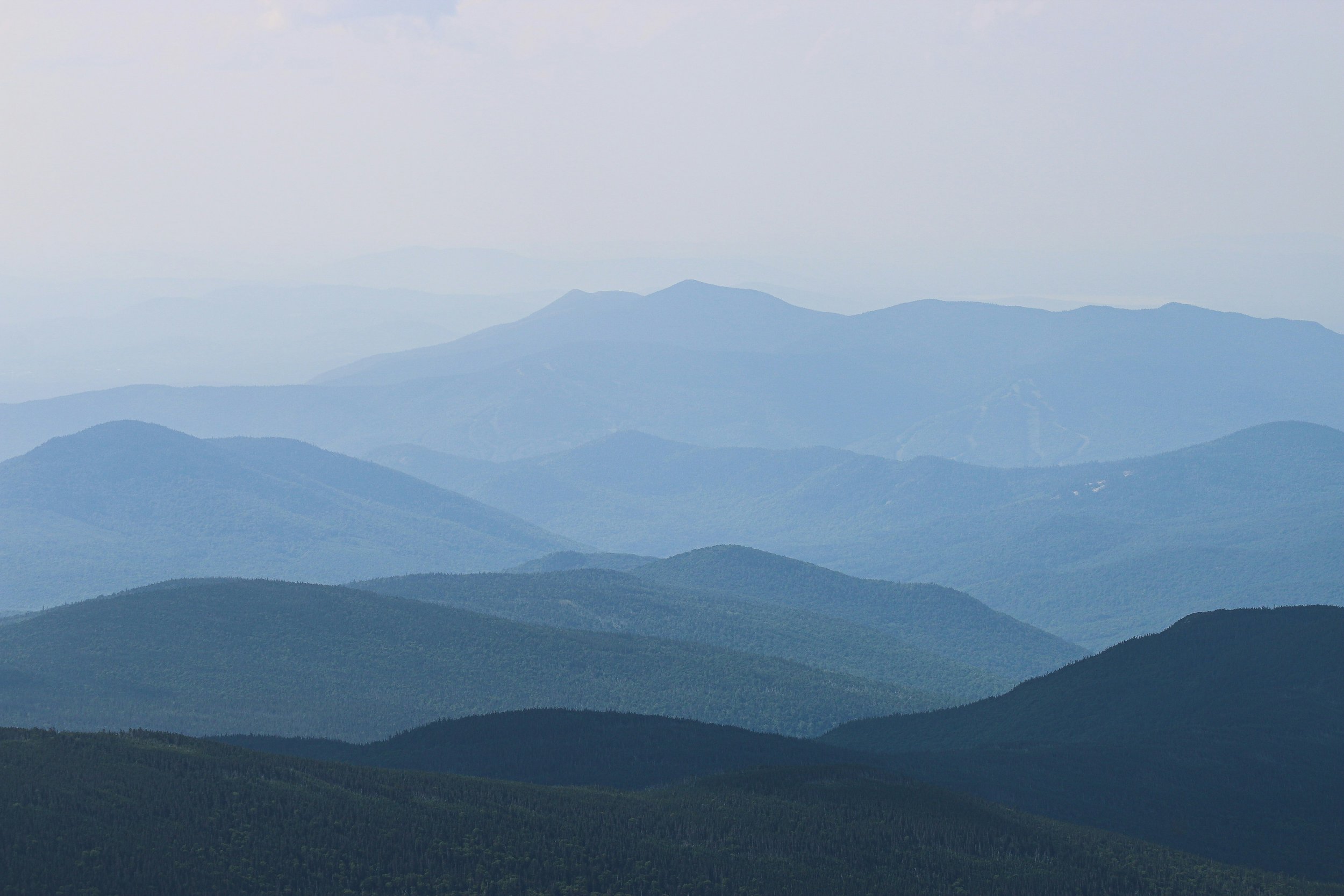 Layers of blue-green mountains under a light gray sky, with some mist or haze in the distance.