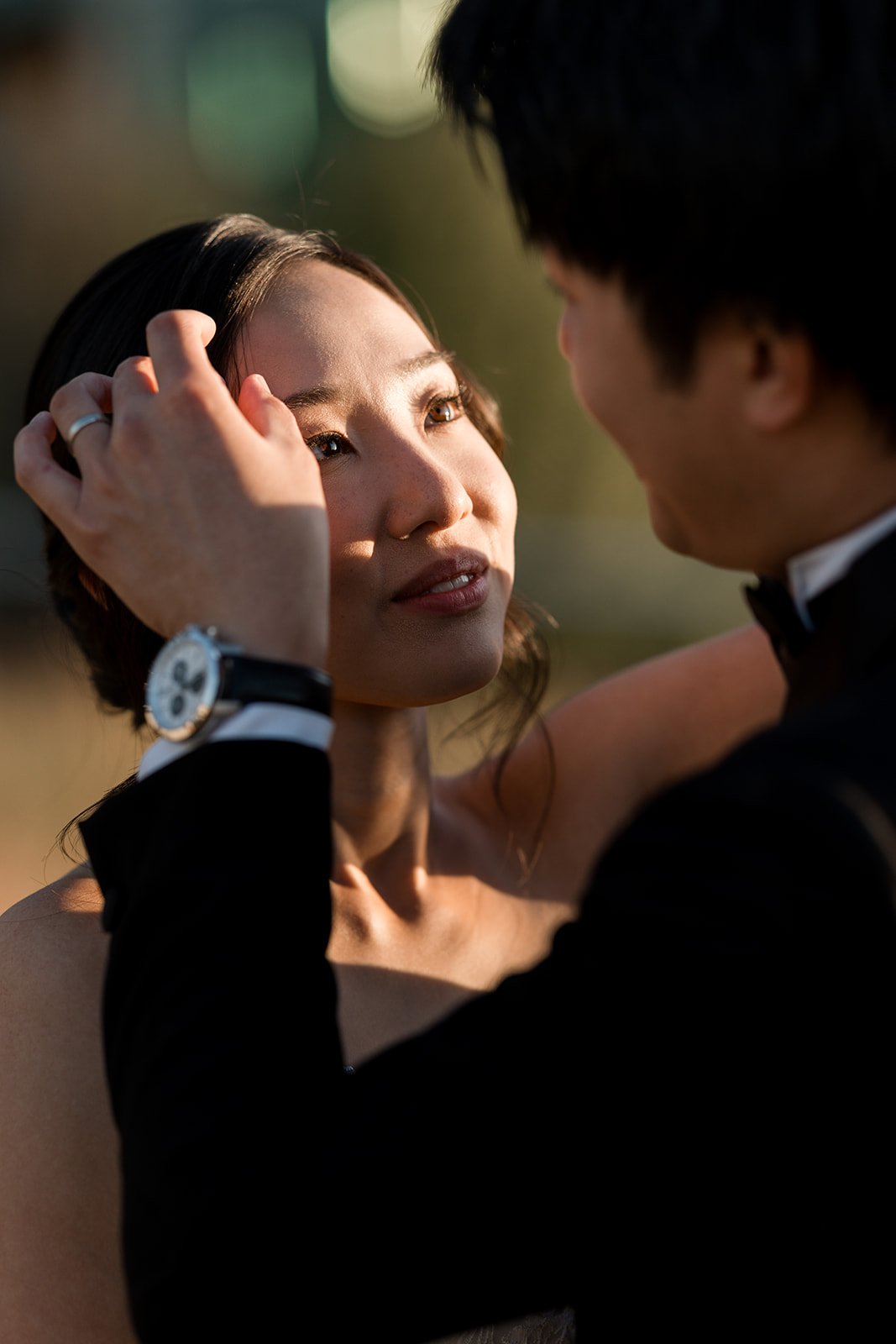 A groom tenderly holds a woman's face as they gaze into each other's eyes on their wedding day in Vancouver BC