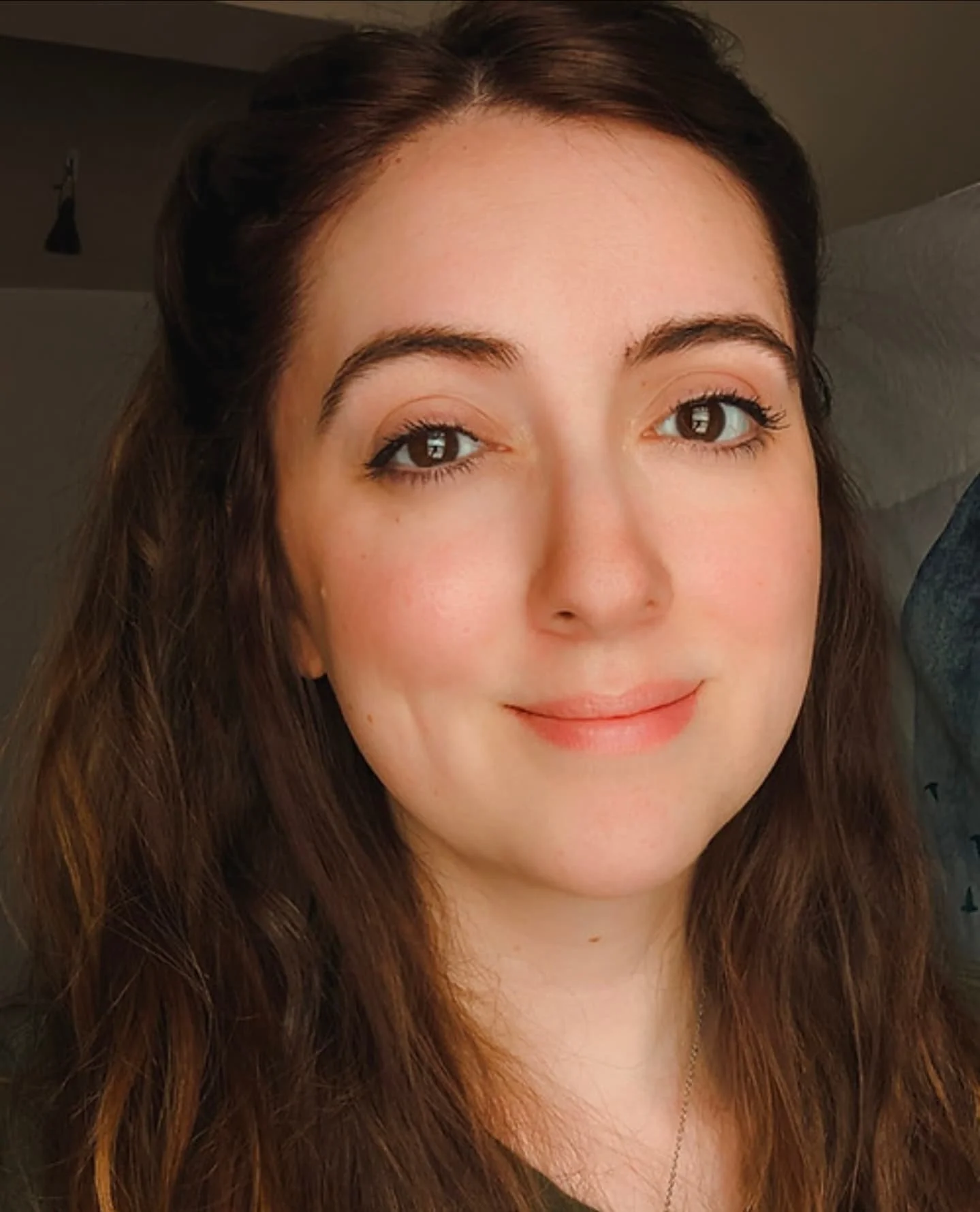 A picture of Kristen, smiling. She has long brown hair and brown eyes with a light skin tone.