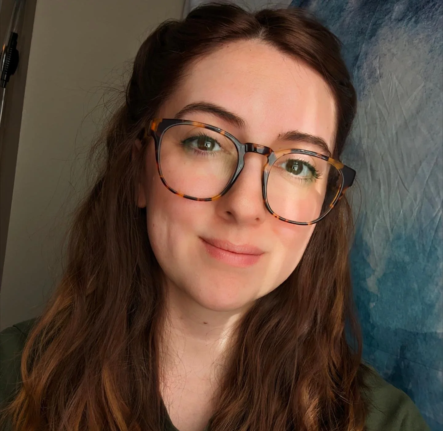 A picture of Kristen with long brown hair, brown eyes, fair skin, and brown glasses.