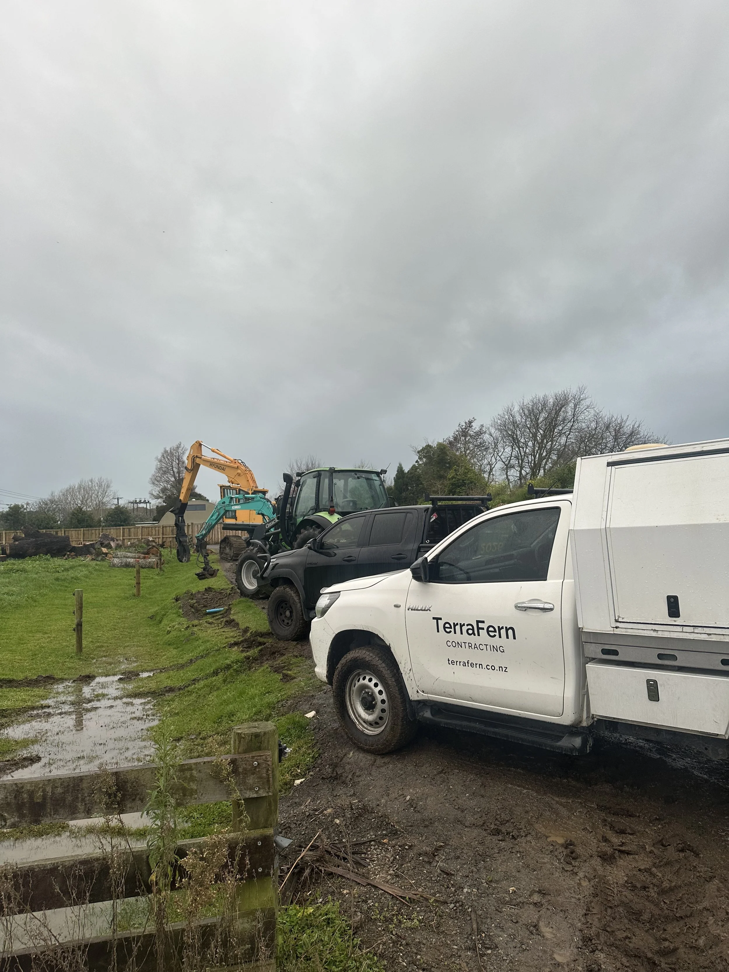 TerraFern Contracting vehicles and pickup truck parked on a muddy work site in Waikato