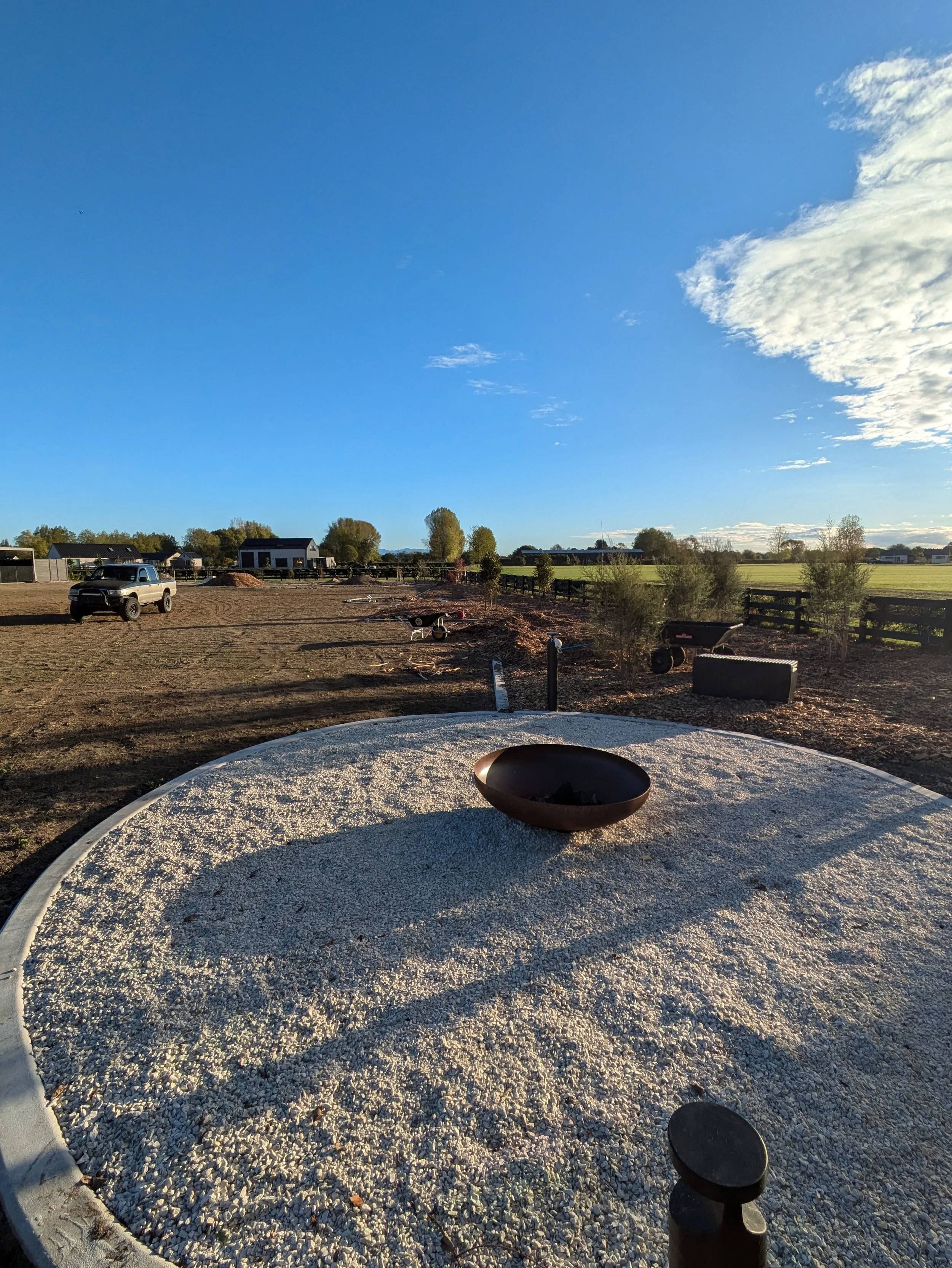 Backyard with a gravel dog run, fire pit and garden border on a rural Waikato property