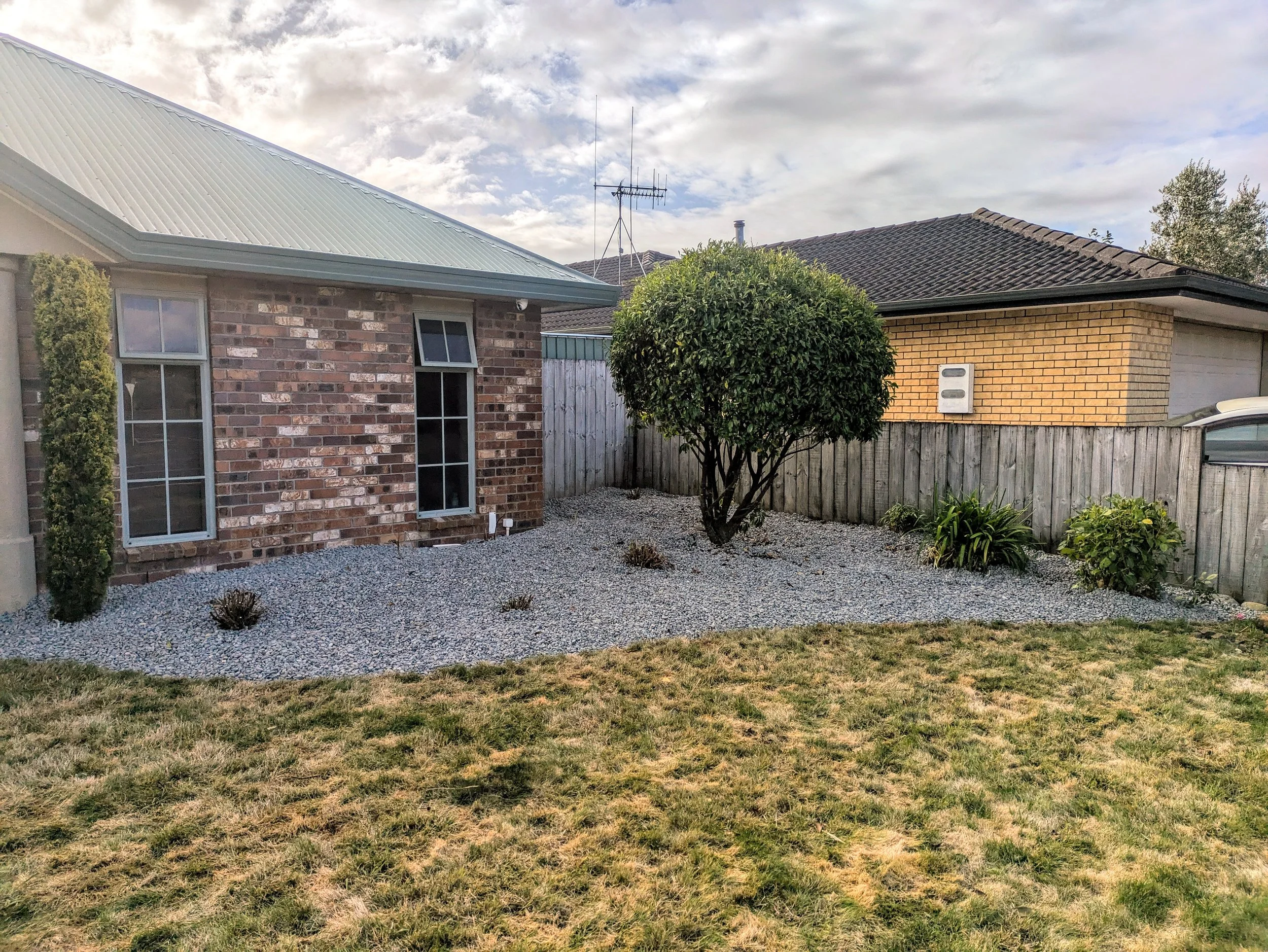 Landscaped backyard with lawn, gravel garden beds, planting and timber fencing