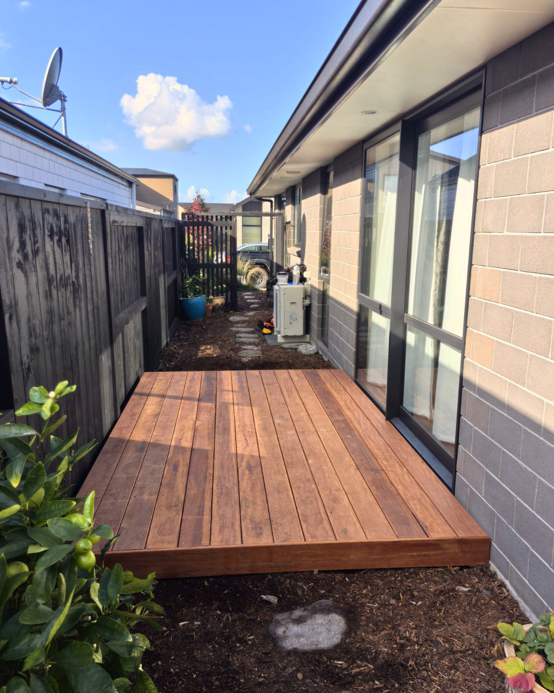 Newly built timber deck attached to a house with sliding doors and fenced backyard