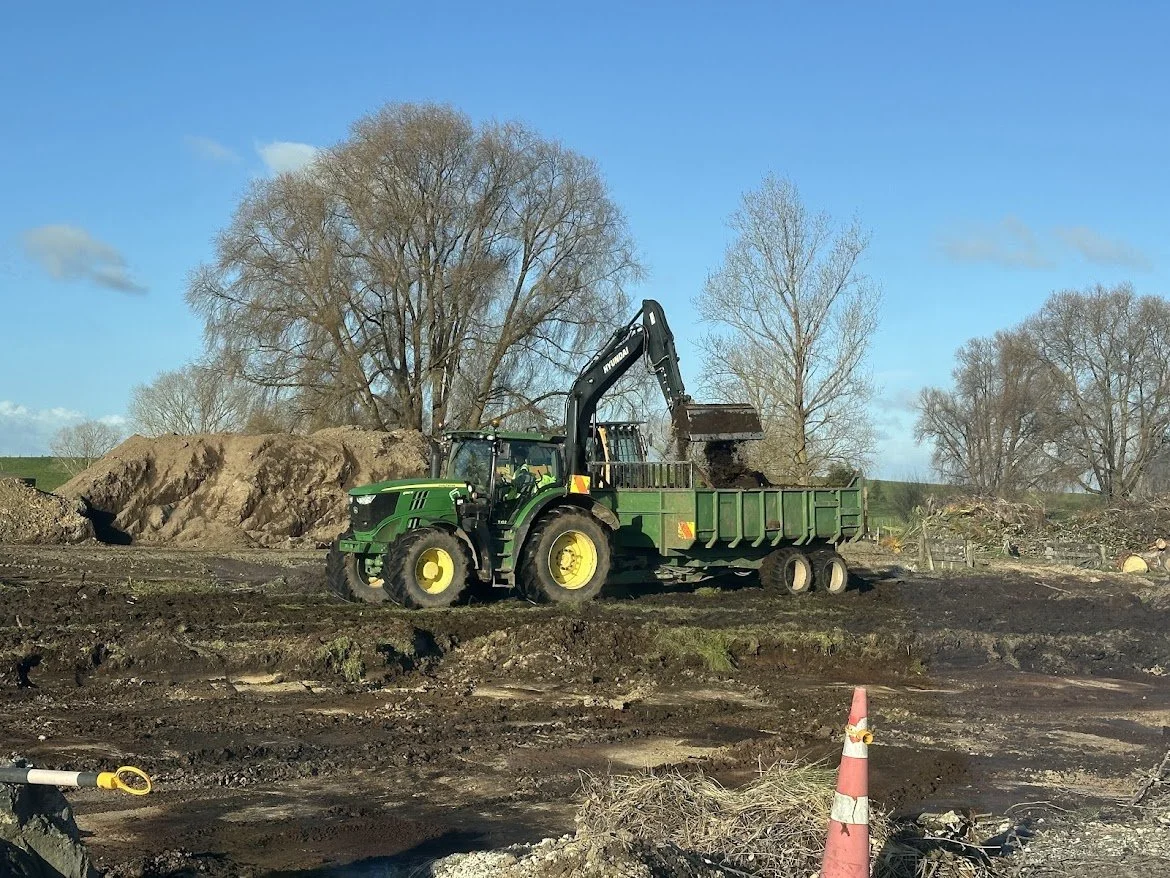 Excavator loading dirt into a tractor and trailer unit at a construction site in Waikato
