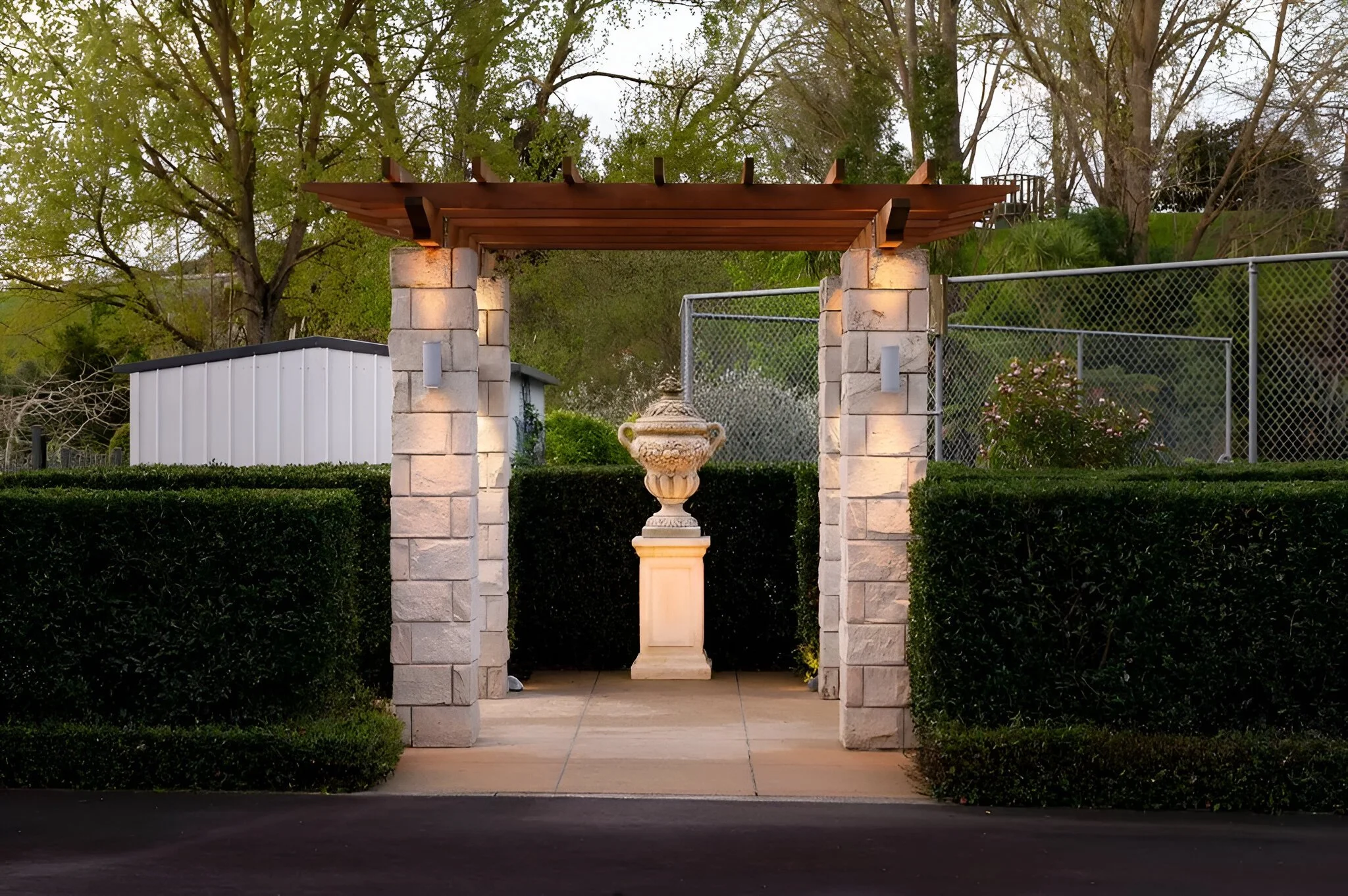 Stone and timber garden entrance feature with landscaping at dusk