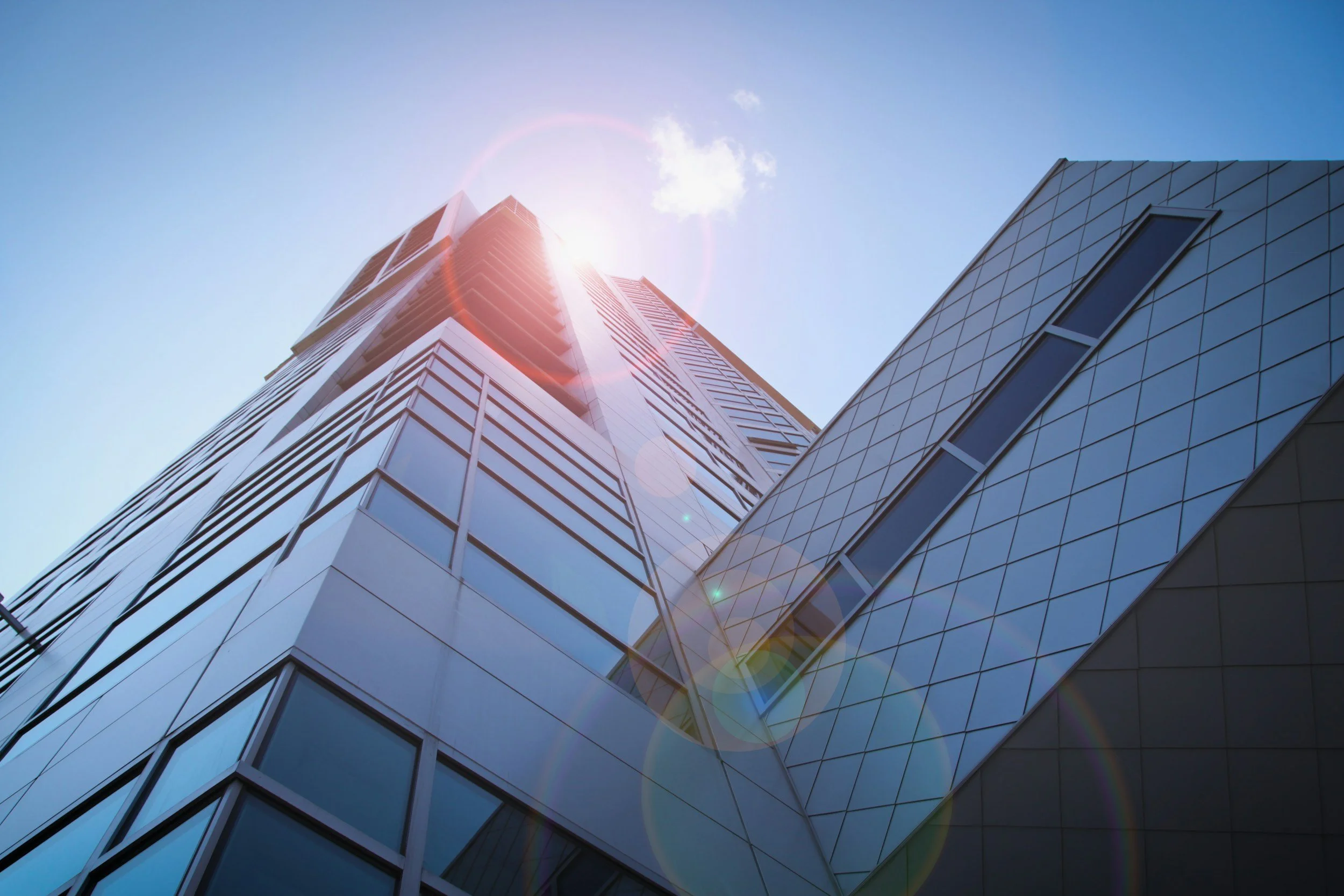 Looking up at modern glass skyscrapers with sunlight creating lens flare