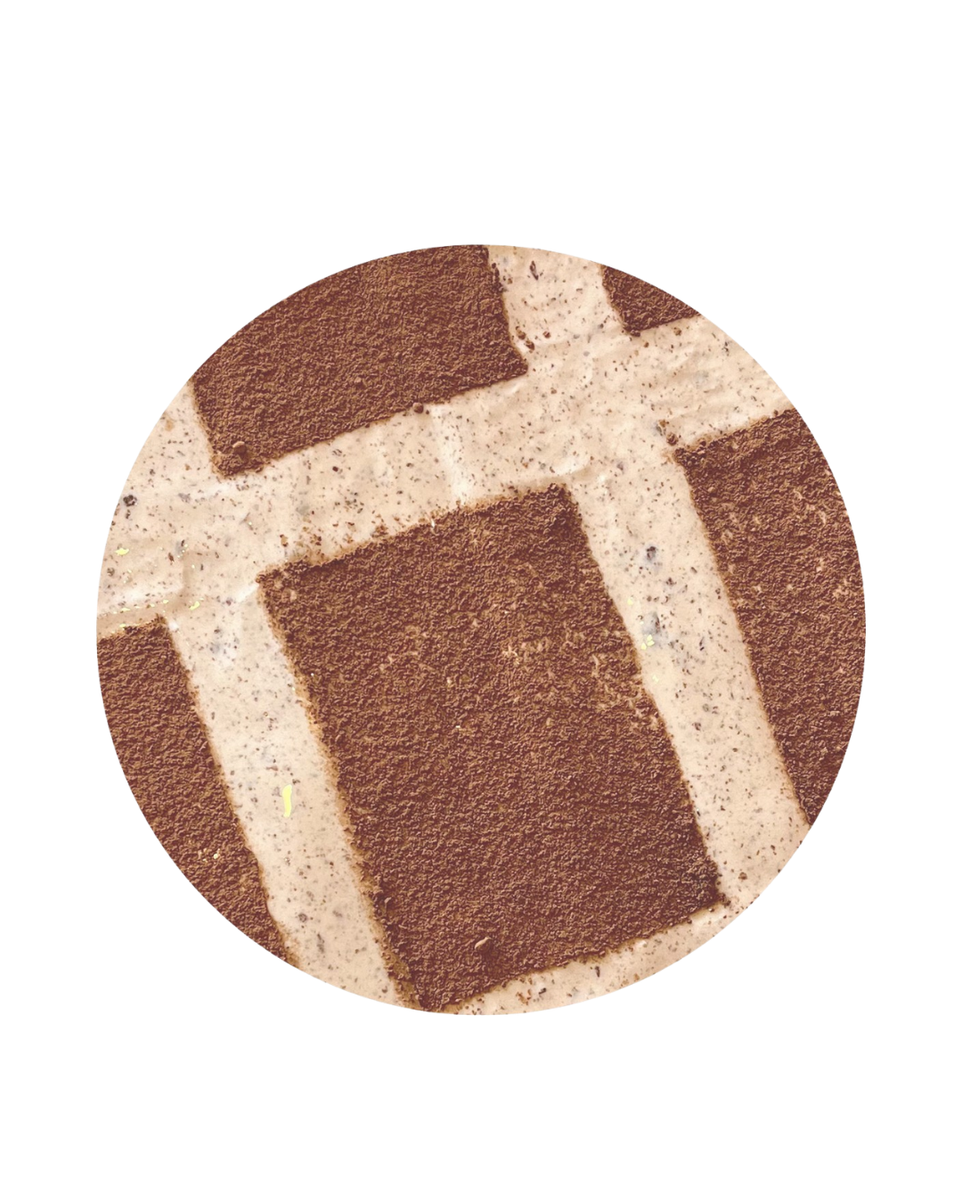 Close-up of a square-shaped chocolate cake topped with cocoa powder and a decorative dusting of powdered sugar, featuring intersecting cream-colored icing lines.