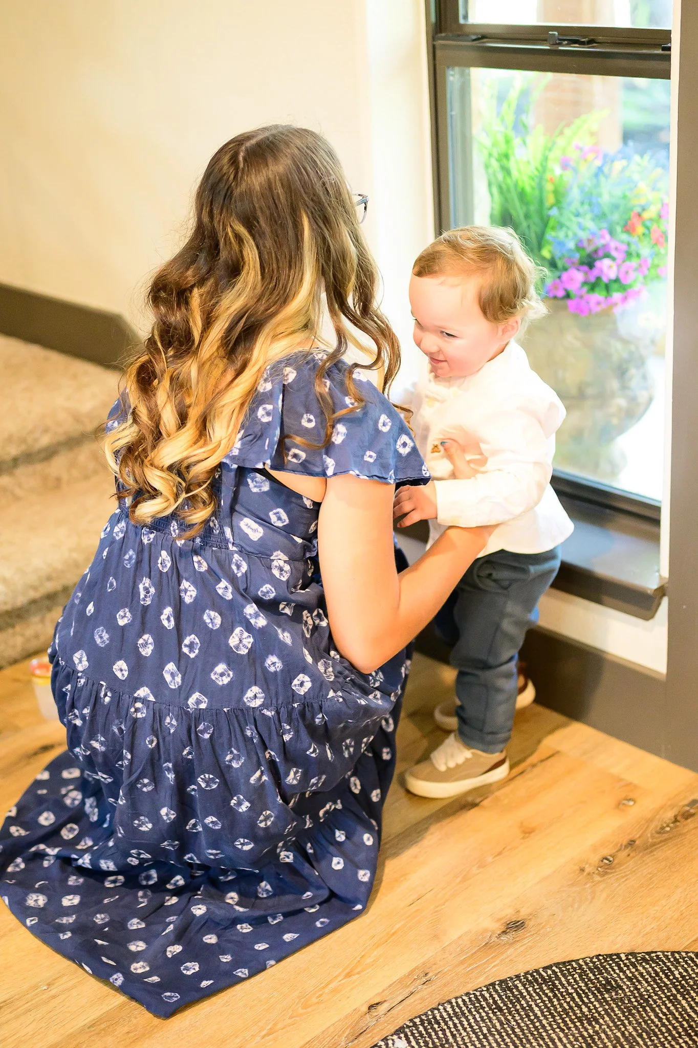 Woman holding a young child beside the large windows in the Main House at The Gathering.
