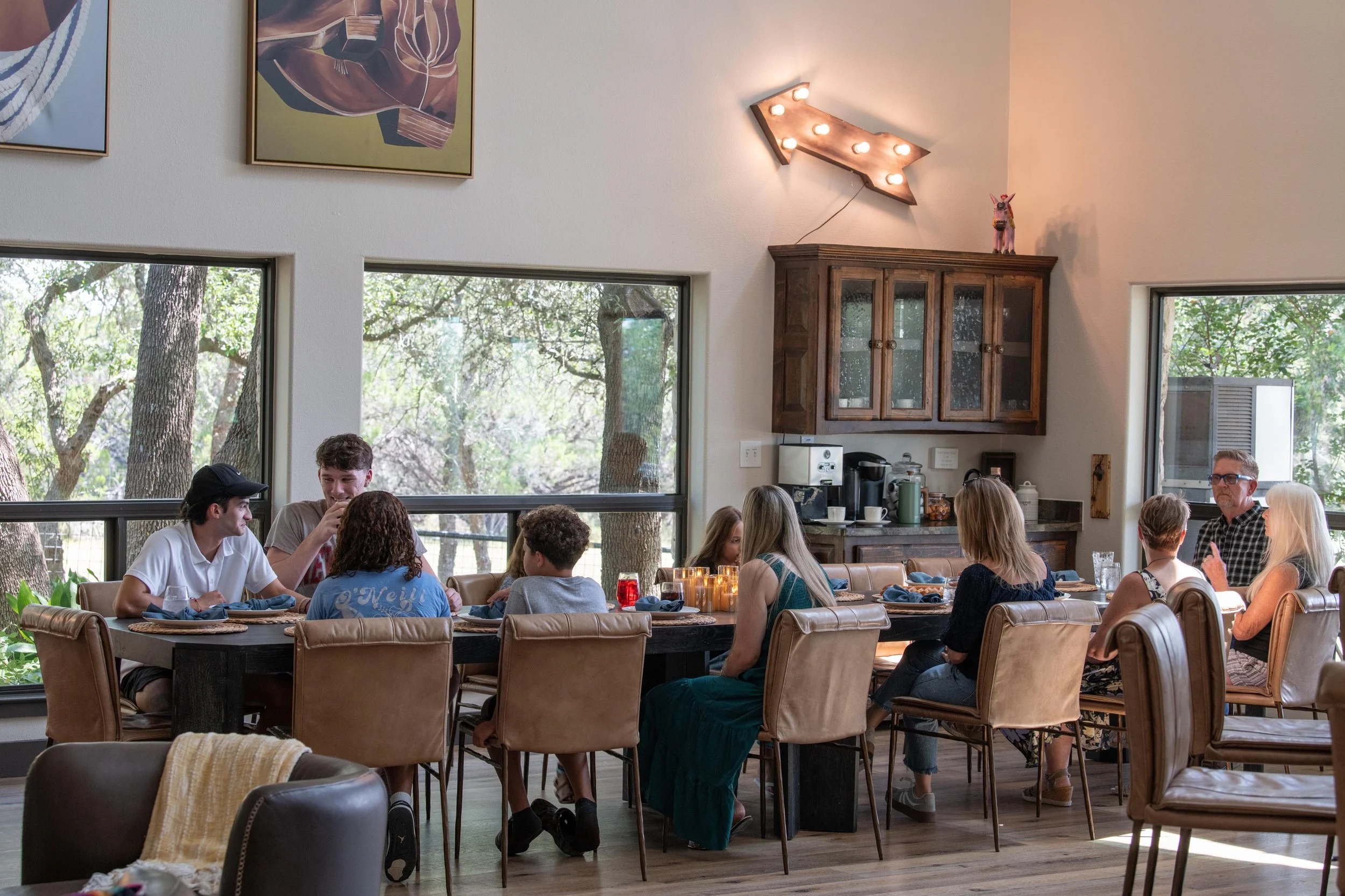 Family gathered around the large dining table in the Main House at The Gathering in Wimberley, Texas.
