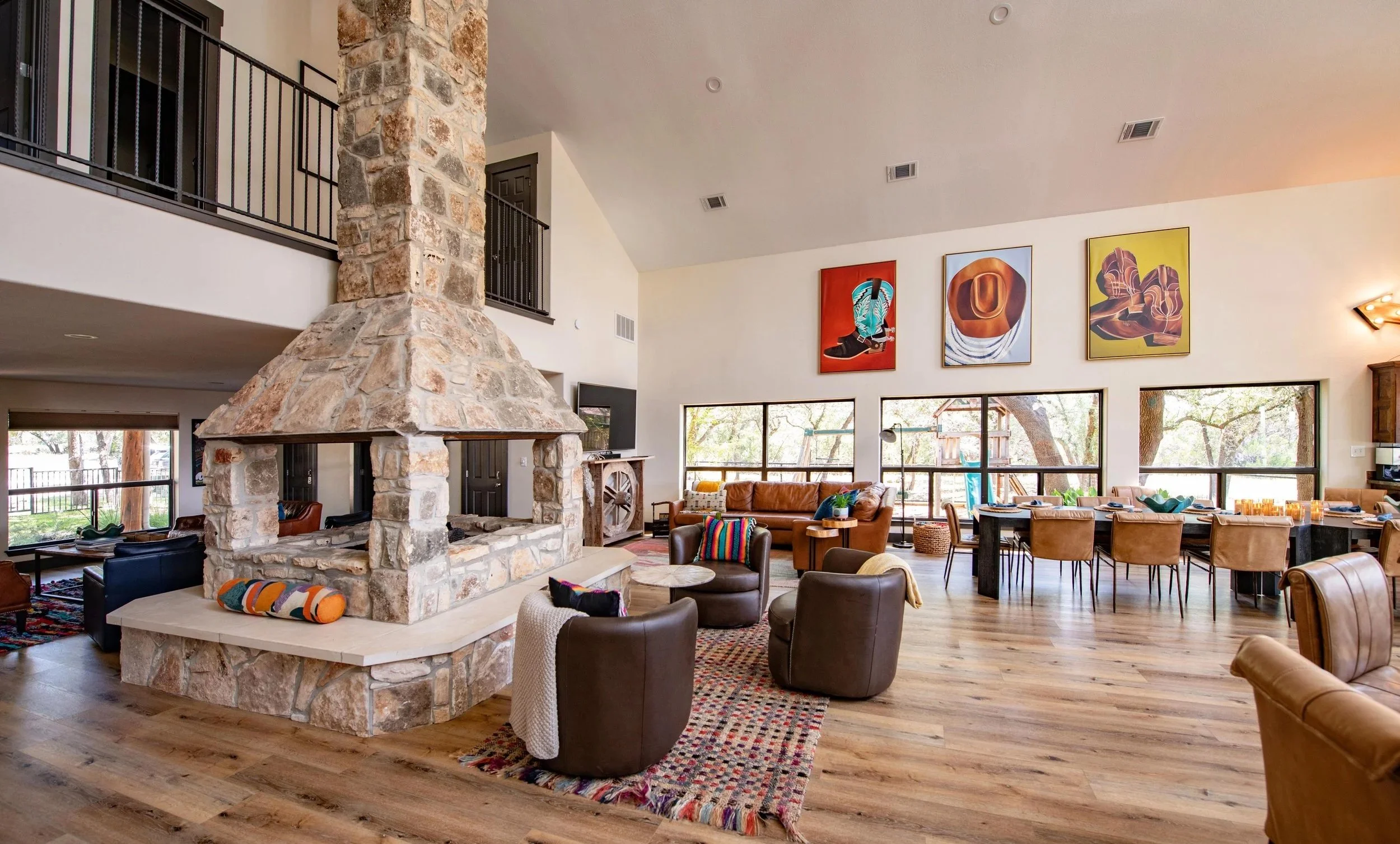 Spacious living and dining area with a stone fireplace and large group dining table at The Gathering in Wimberley, Texas.