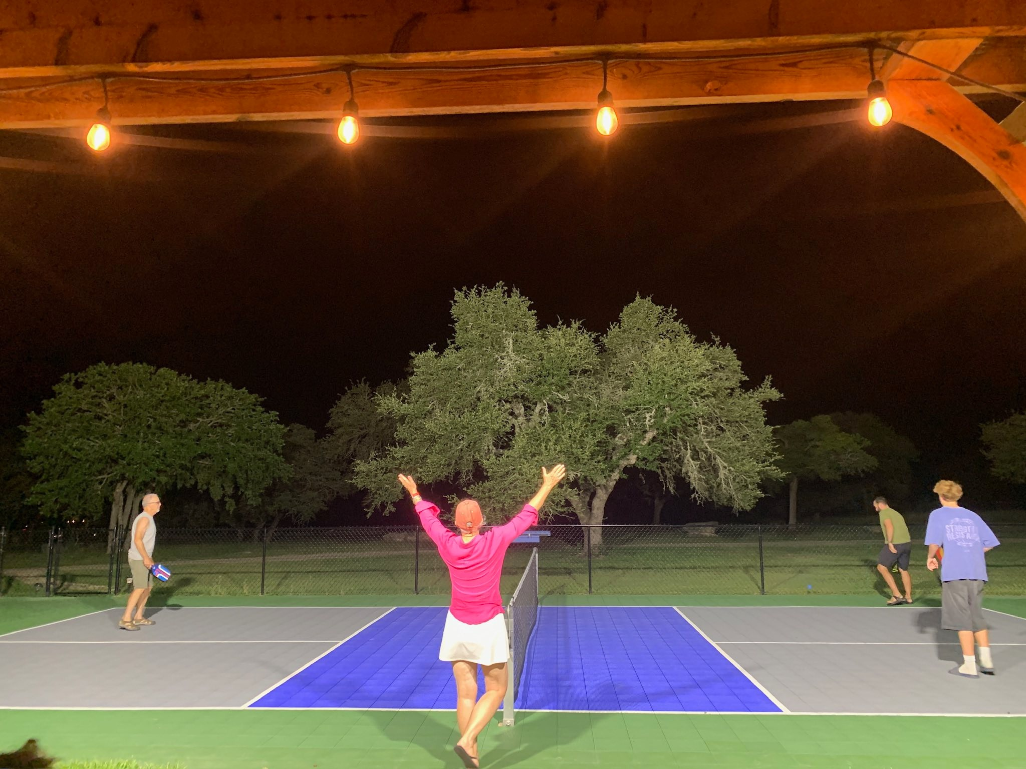 Guests playing pickleball at night on the lighted court.
