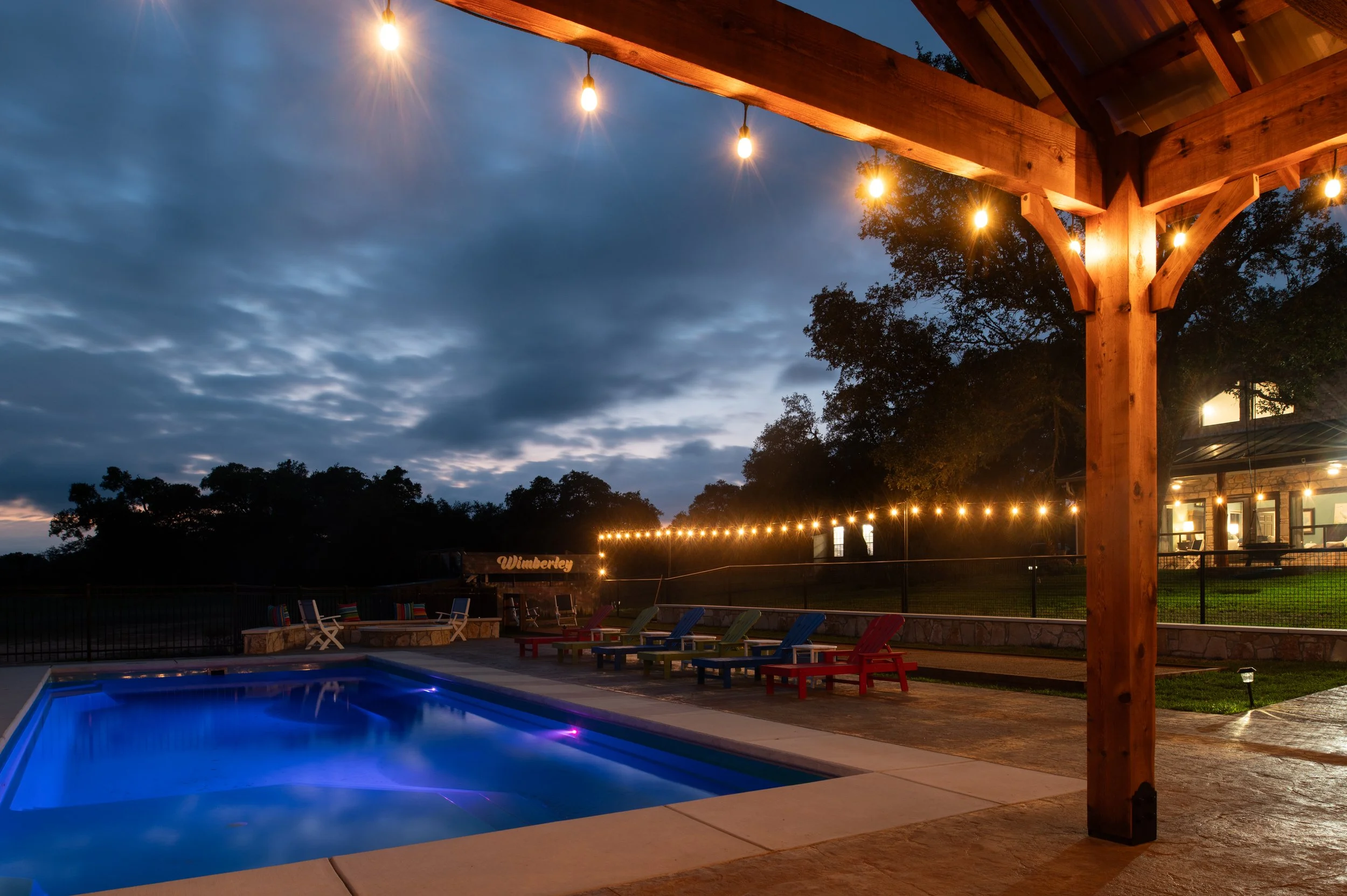 The swimming pool and outdoor pavilion illuminated at night.