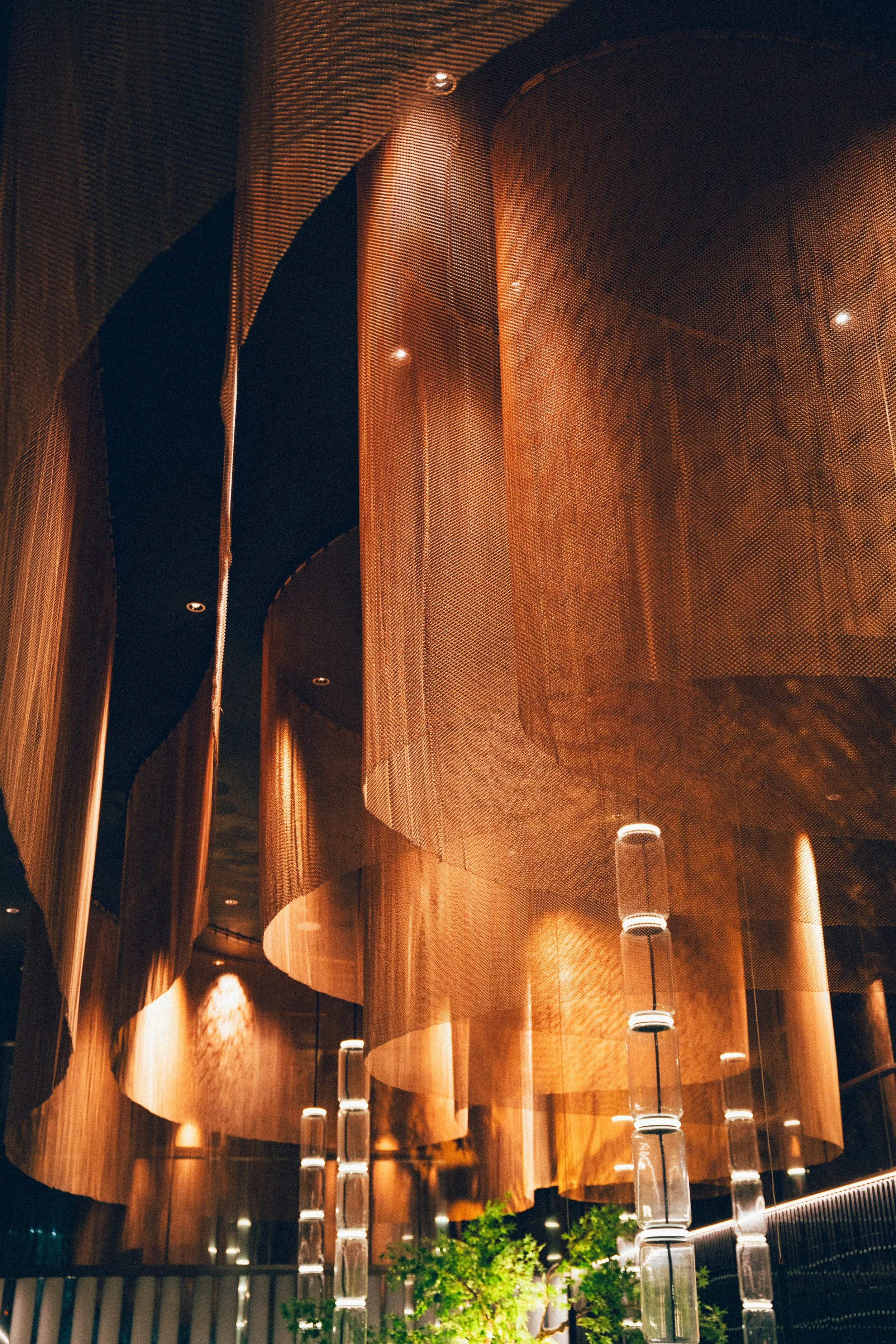 Une architecture intérieure moderne avec des structures en forme d'arcs en bois et des lampes suspendues.