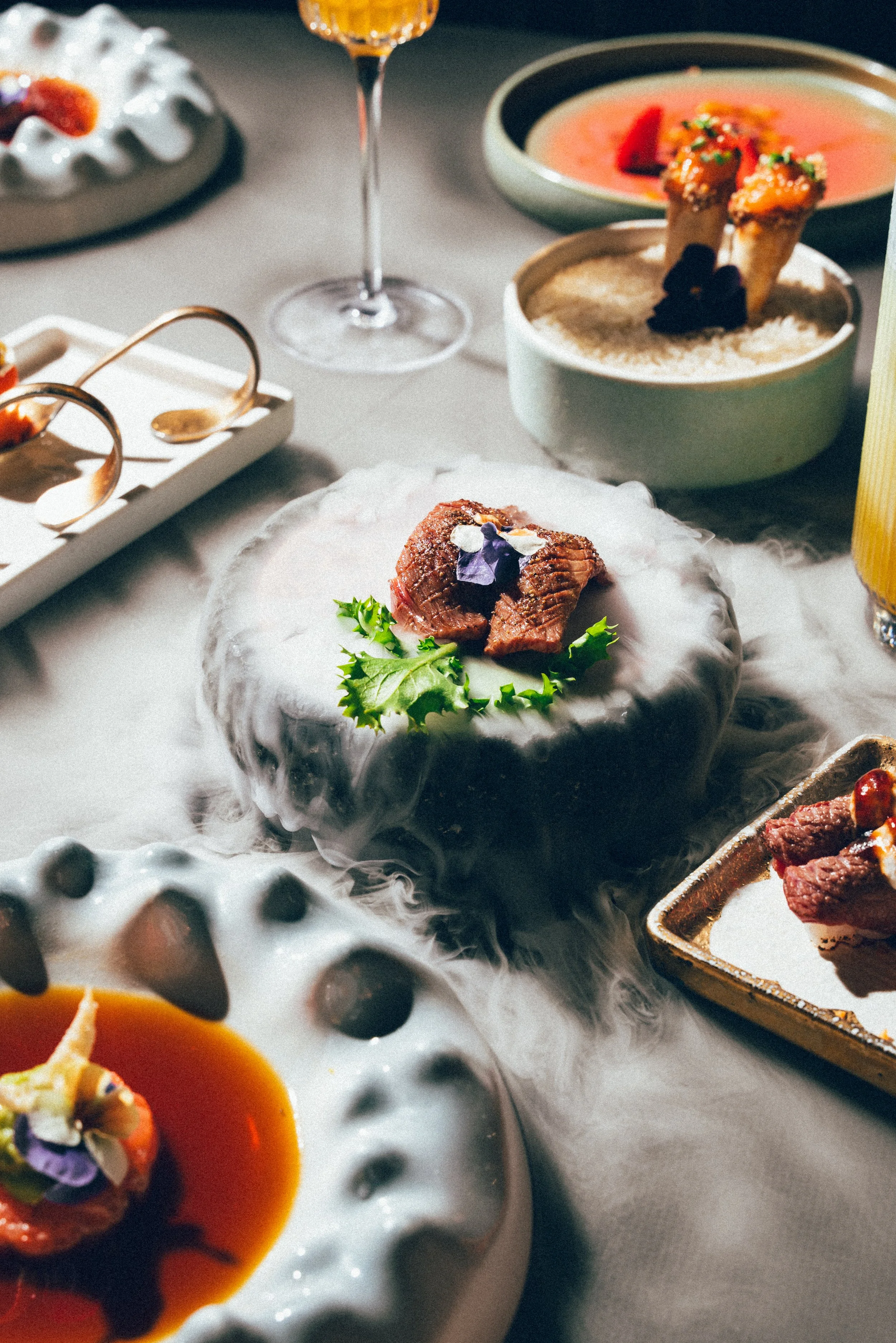 Assortiment de plats gastronomiques avec de la viande, des sauces et des desserts, présentation raffinée sur des plats élégants.