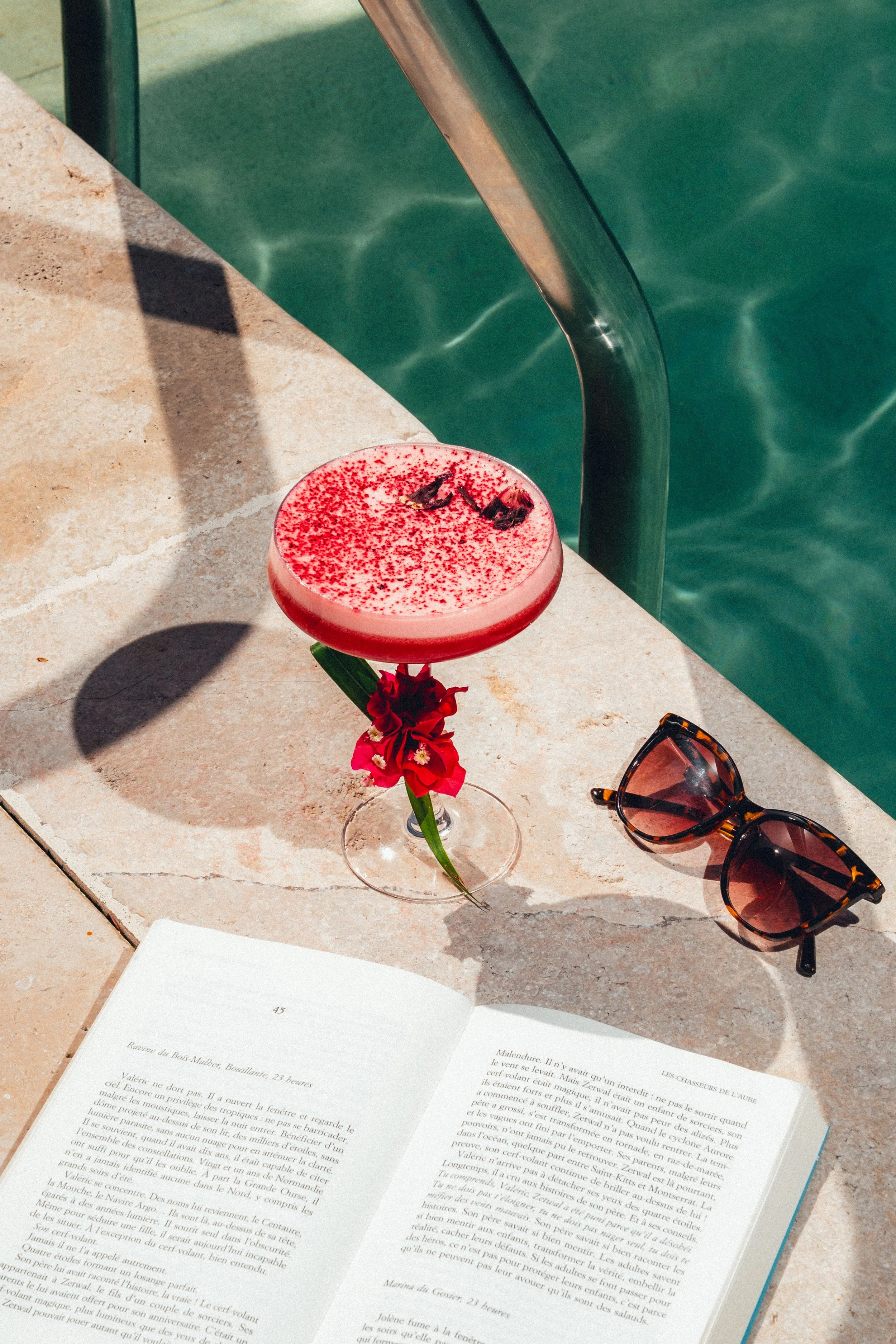 Un cocktail rose près d'une piscine.