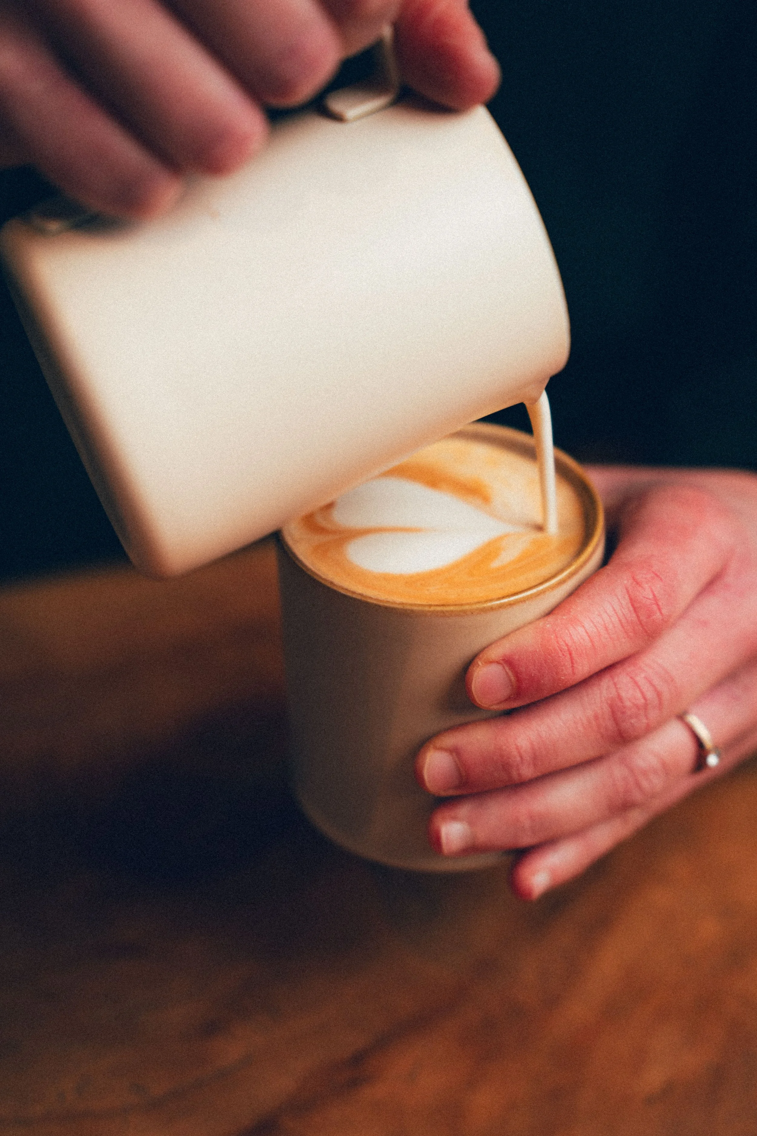 Une main tenant une tasse blanche, en train de verser une boisson dans la tasse.