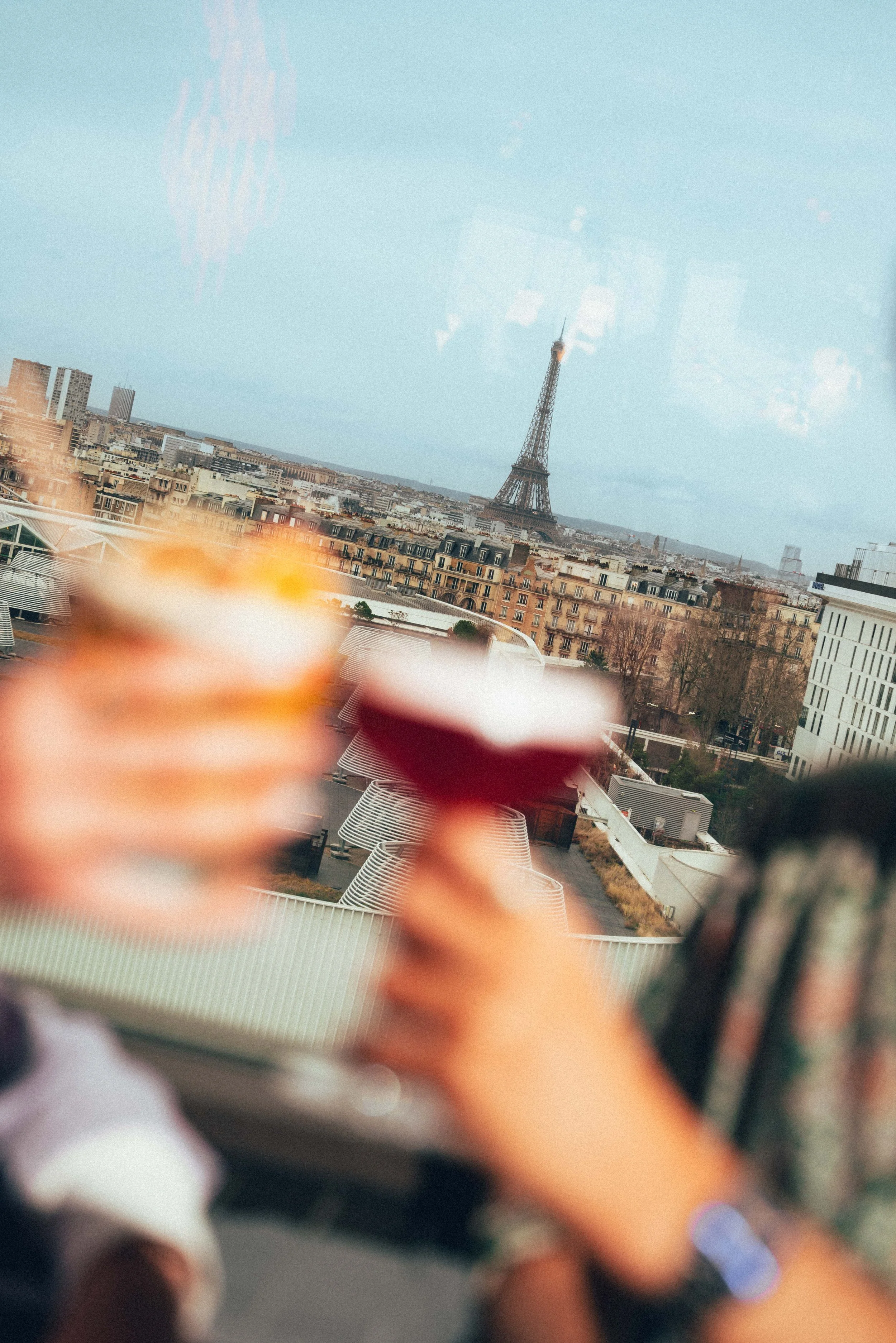 Vue floue de la ville de Paris avec la Tour Eiffel en arrière-plan, vue à travers une fenêtre avec une personne en premier plan
