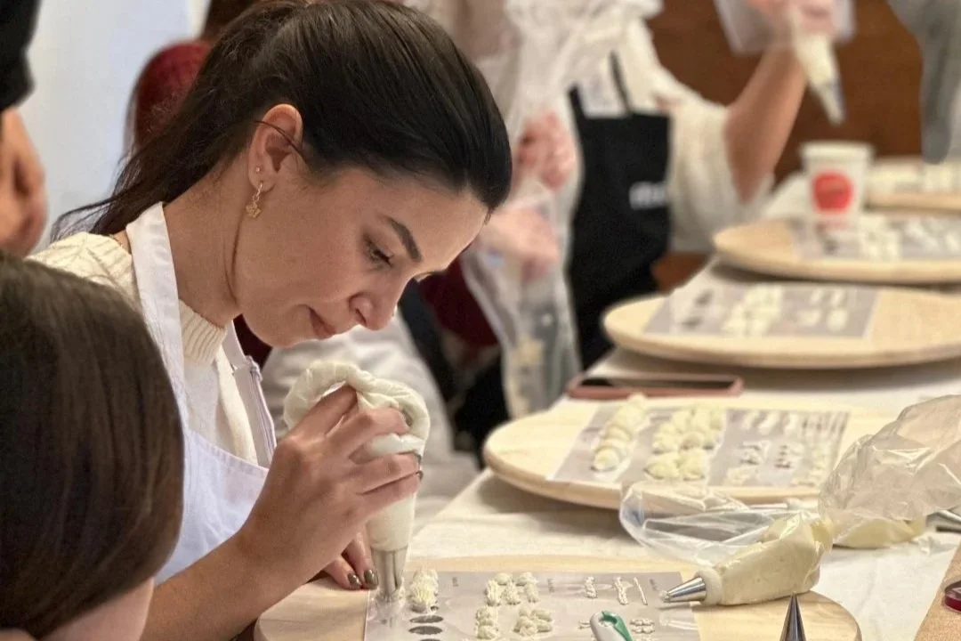 Rapariga a decorar bolos usando um saco de pasteleiro, durante um workshop.