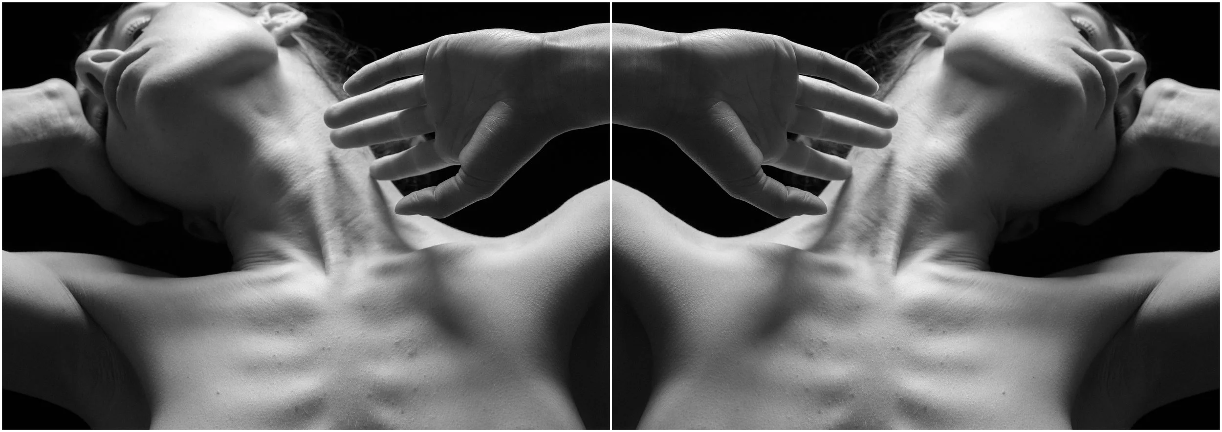 A black and white mirror-reflection photographic portrait of a young woman. A close-up. The clavicule, neck and the chest articulations showcased. Hands hold the head. Very strong shadows and contrasts.