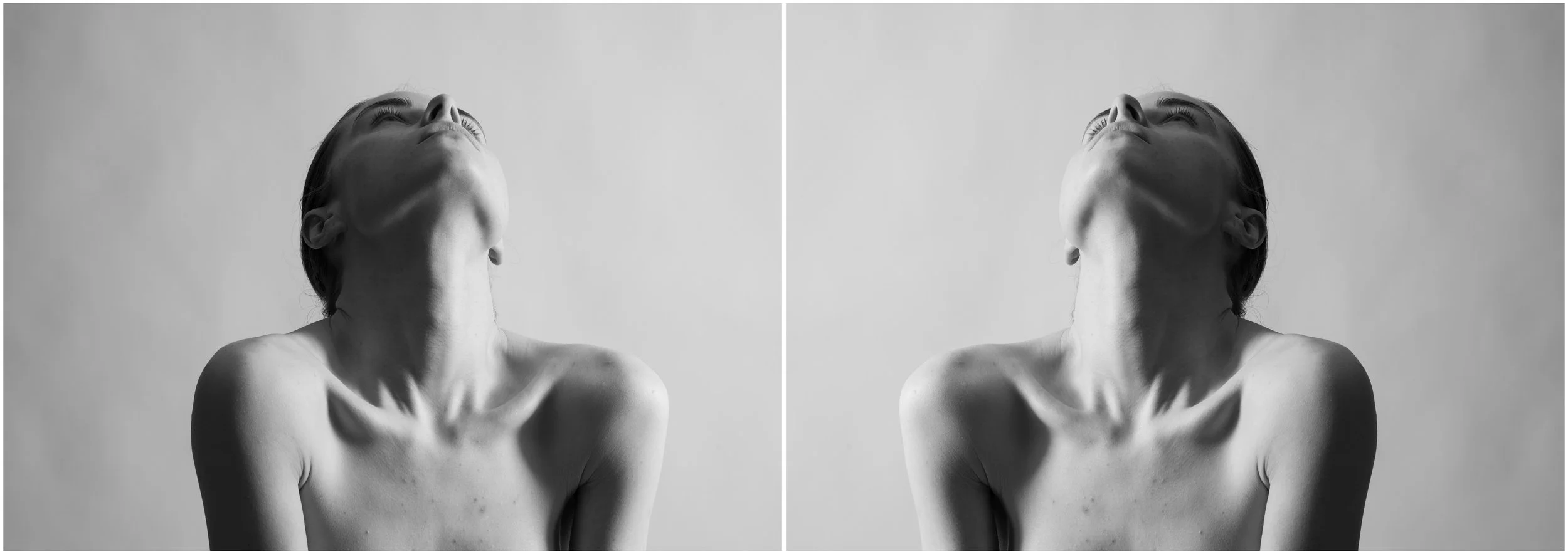 A black and white mirror-reflection portrait of a young woman. She is looking up. Her face is hidden. Very strong shadows and contrasts.