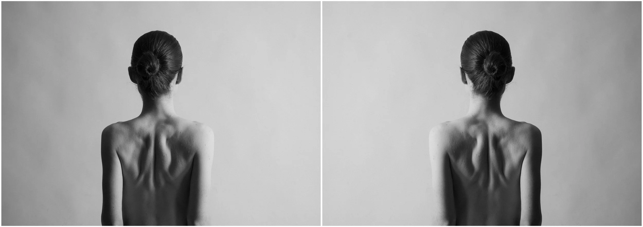 A black and white mirror-reflection portrait of a back of a young woman. She is looking away from the camera. Her face is hidden. Visible muscular tension on her back. Very strong shadows and contrasts.