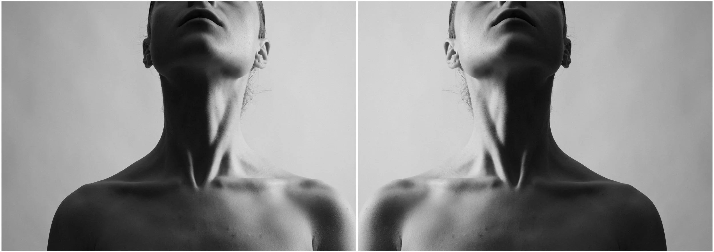 A black and white mirror-reflection photographic portrait of a young woman. The photo is cropped so that the upper part of her head is not visible. She is looking up, exhibiting her chest and her neck clearly. Very strong shadows and contrasts.