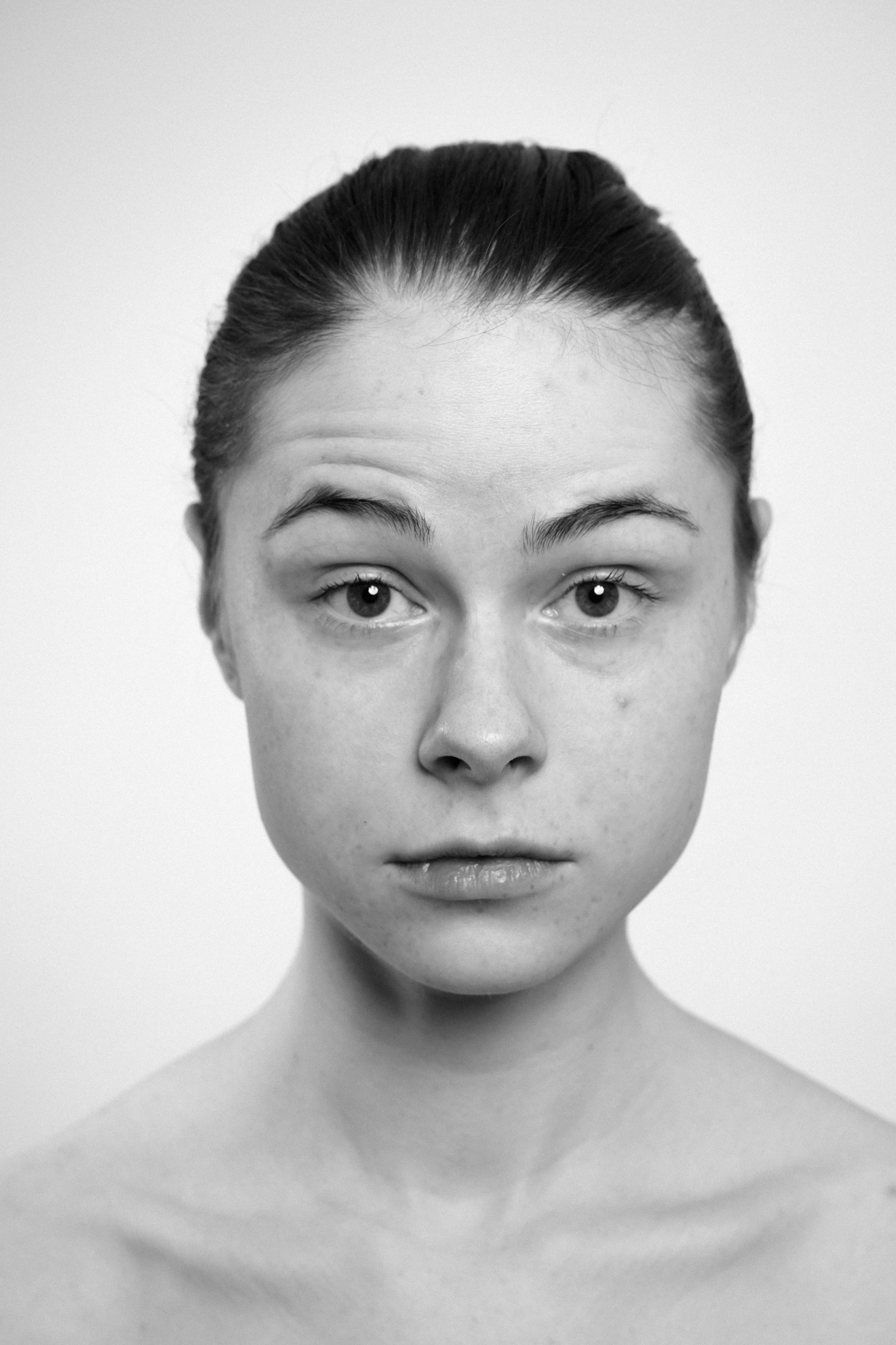 Studio portrait of a young woman in black and white. She lifts her eyebrow. She makes faces, grimaces.