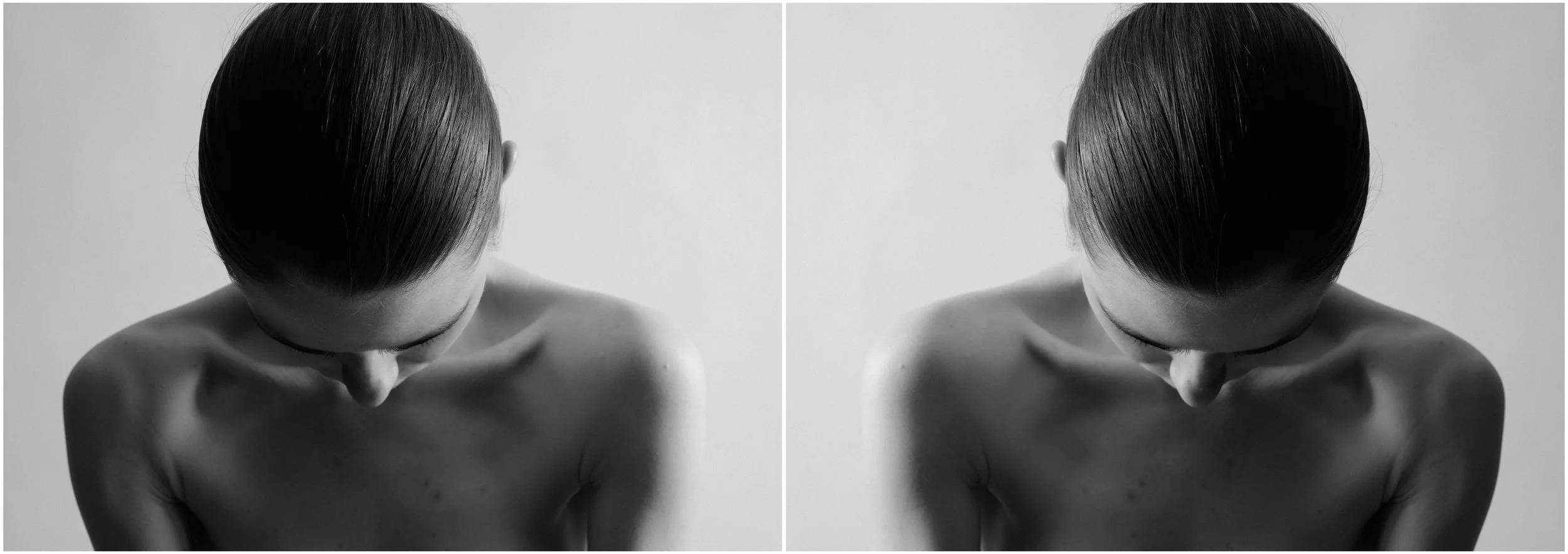 A black and white mirror-reflection portrait of a young woman. She is looking down. Her face is hidden. Very strong shadows and contrasts.