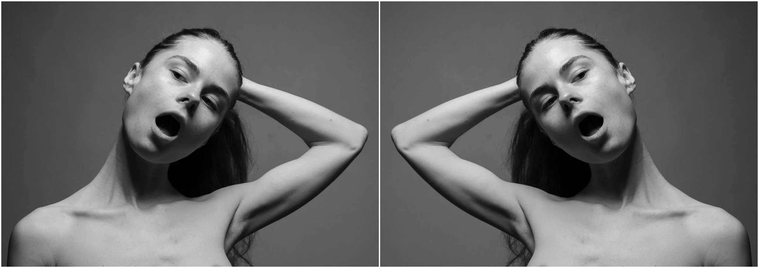 A black and white mirror-reflection photographic portrait of a young woman. A close-up. She is looking up with her eyes slightly closed. She holds her hair, tight up, in her hand. Her mouth is open as if in shock. Very strong shadows and contrasts.
