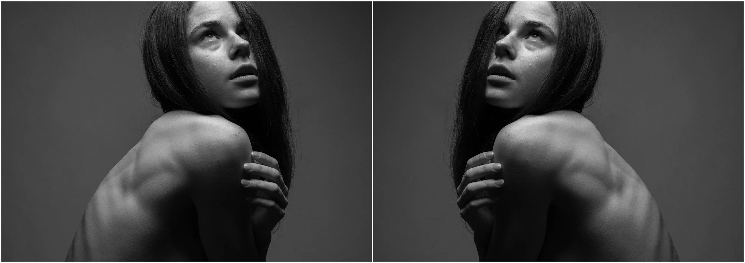 A black and white mirror-reflection photographic portrait of a young woman. A close-up. She is looking up, her profile is visible. Her muscular back is seen. Very strong shadows and contrasts.