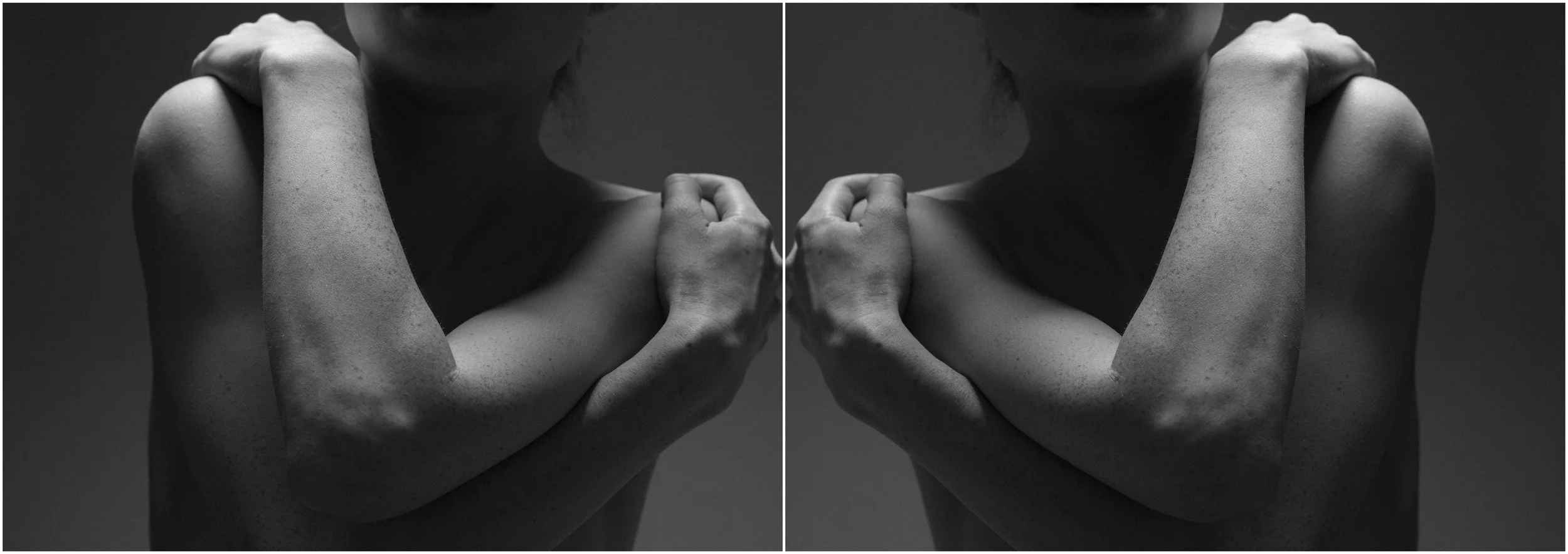 A black and white mirror-reflection photographic portrait of a young woman. A close-up. The arms crossed in front of the body. Very strong shadows and contrasts.